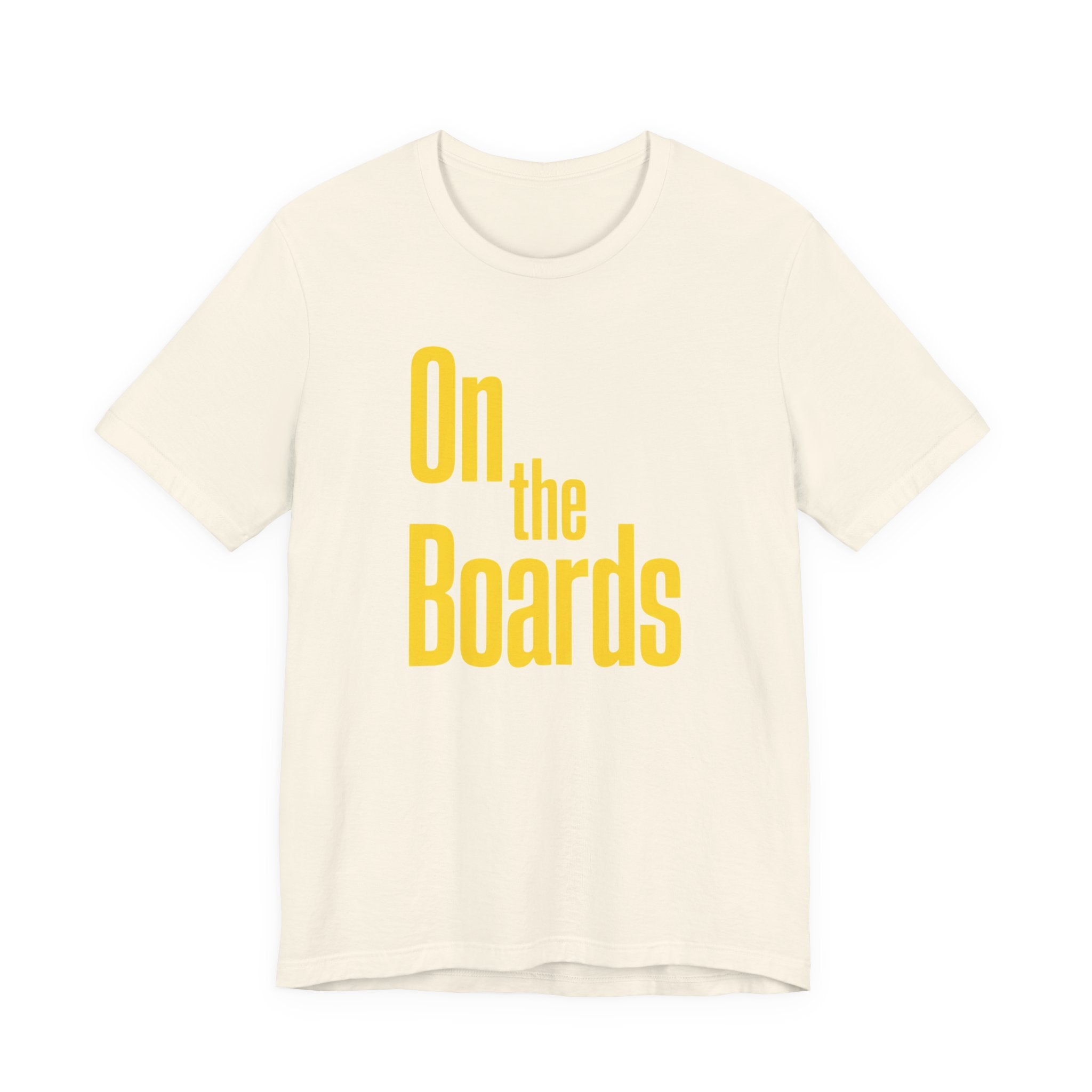 Beige t-shirt with 'On the Boards' text in yellow on a white background
