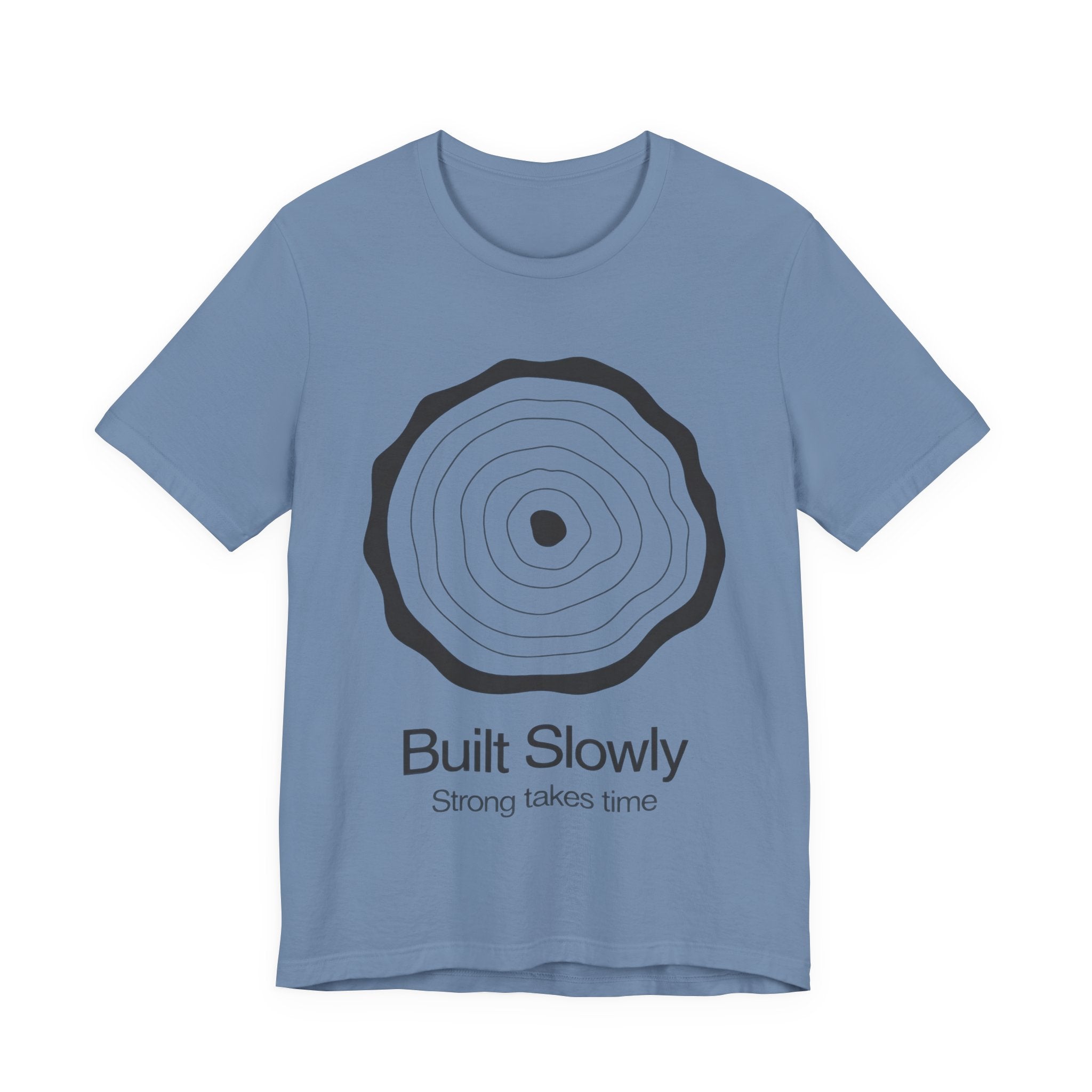 Blue t-shirt with black circular design and text 'Built Slowly Strong takes time' on a white background