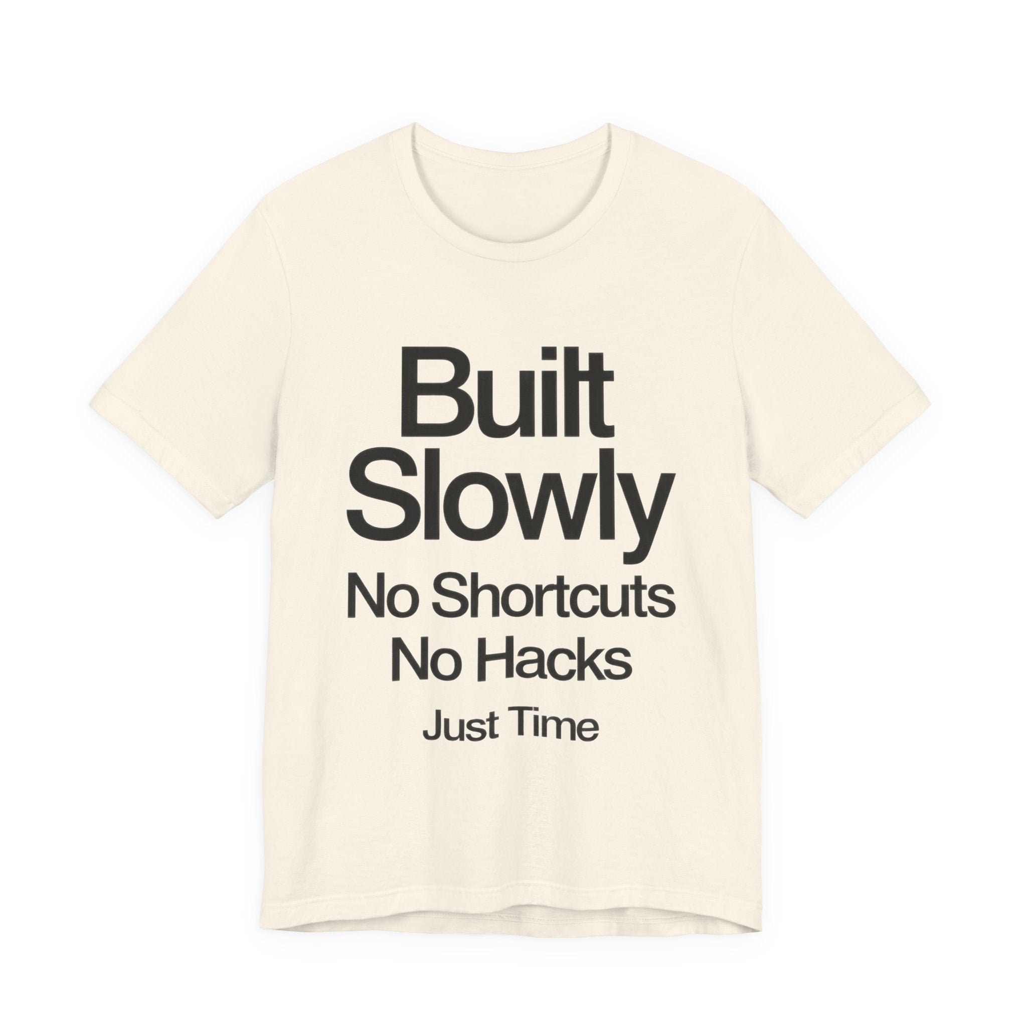 Beige t-shirt with black text 'Built Slowly No Shortcuts No Hacks Just Time' on a white background