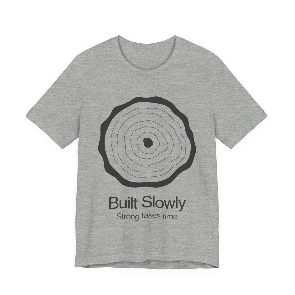 Gray t-shirt with a circular design and text 'Built Slowly Strong takes time' on a white background