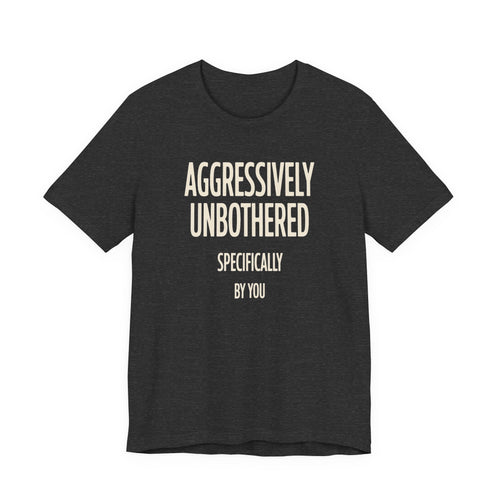 Dark grey t-shirt with text 'AGGRESSIVELY UNBOTHERED SPECIFICALLY BY YOU' on a white background