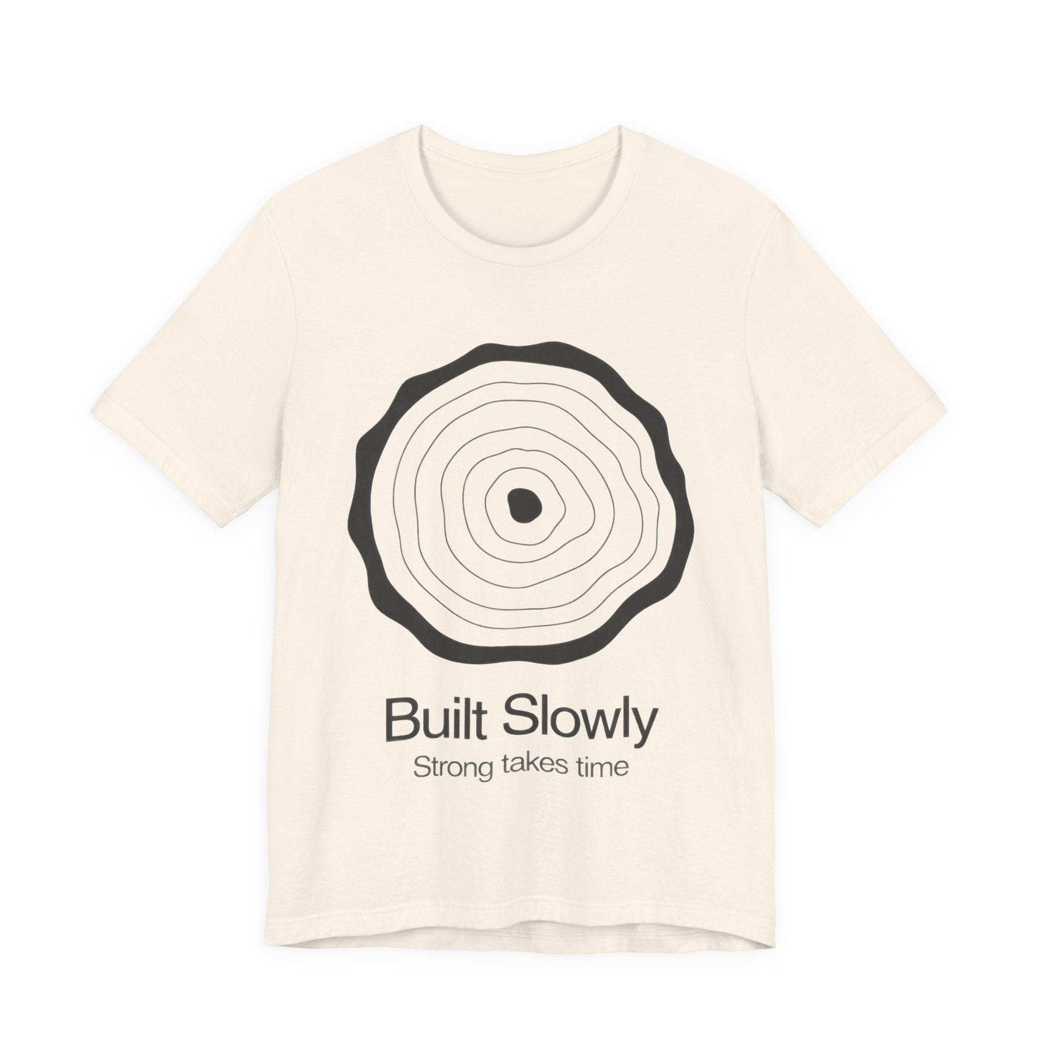 Beige t-shirt with black tree ring design and text 'Built Slowly Strong takes time' on a white background