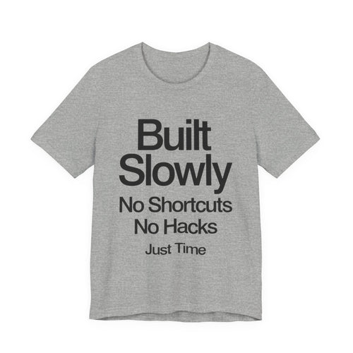 Gray t-shirt with black text 'Built Slowly No Shortcuts No Hacks Just Time' on a white background