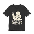 Black t-shirt with a snail and camera graphic and text 'Slow Film Slow Life Frame First' on a white background