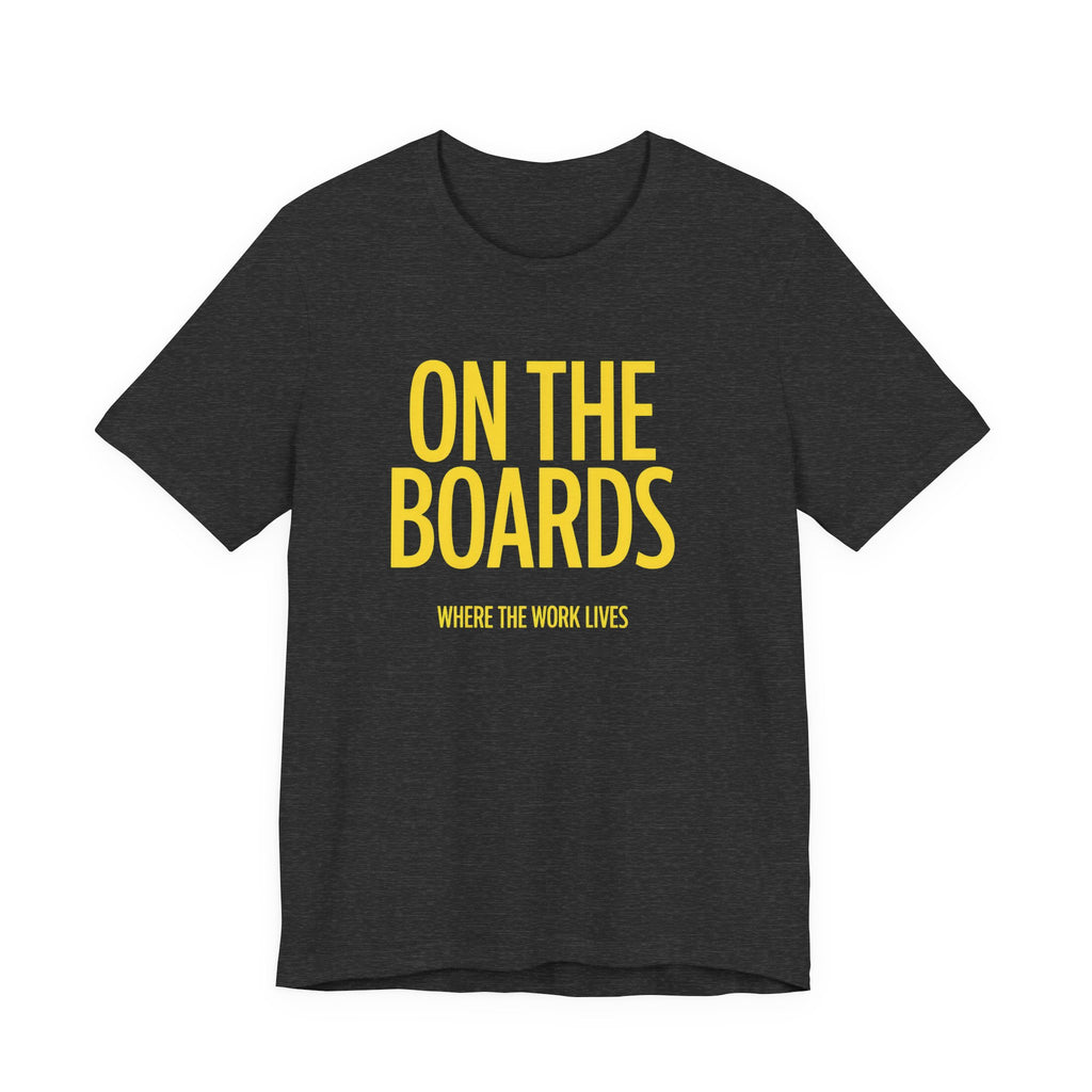 Black t-shirt with yellow text 'ON THE BOARDS WHERE THE WORK LIVES' on a white background