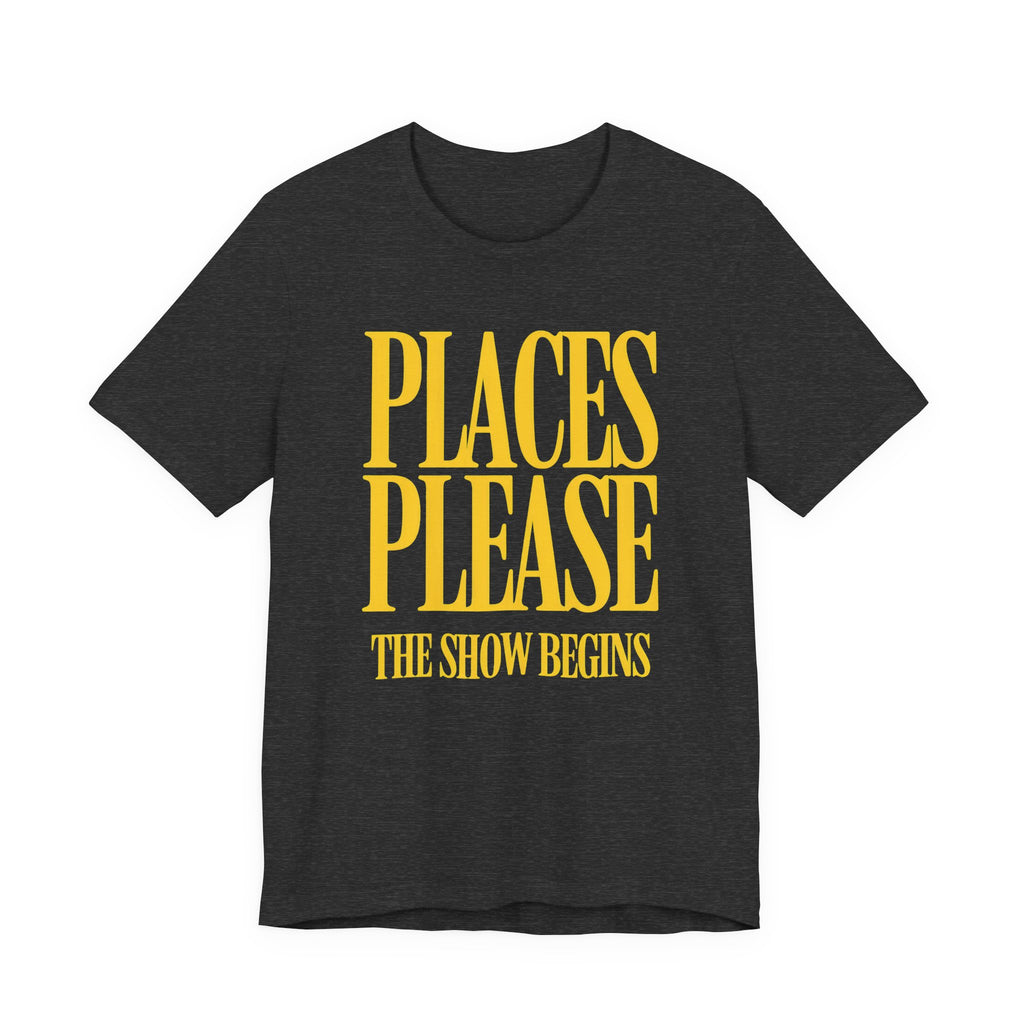 Black t-shirt with yellow text 'PLACES PLEASE THE SHOW BEGINS' on a white background
