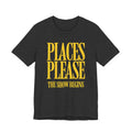 Black t-shirt with yellow text 'PLACES PLEASE THE SHOW BEGINS' on a white background