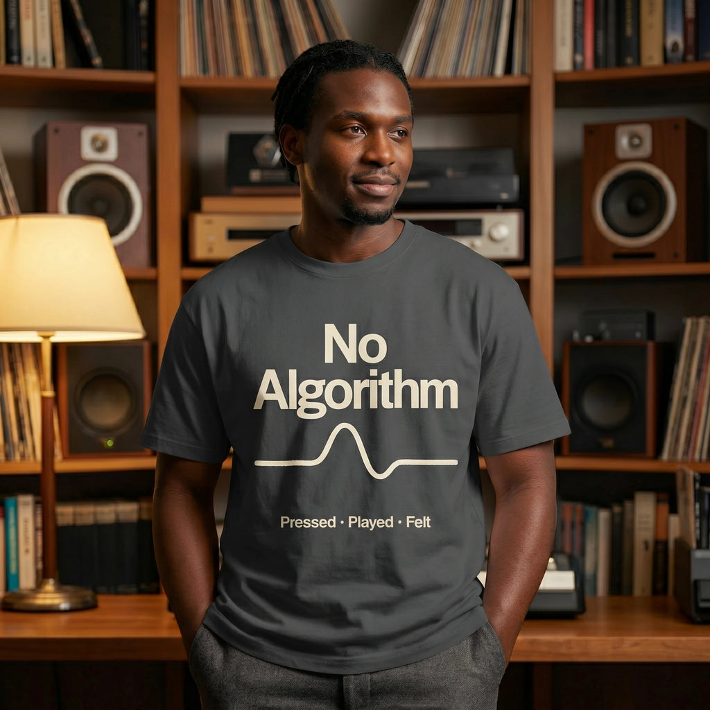Man wearing a 'No Algorithm' t-shirt in a room with bookshelves and audio equipment.
