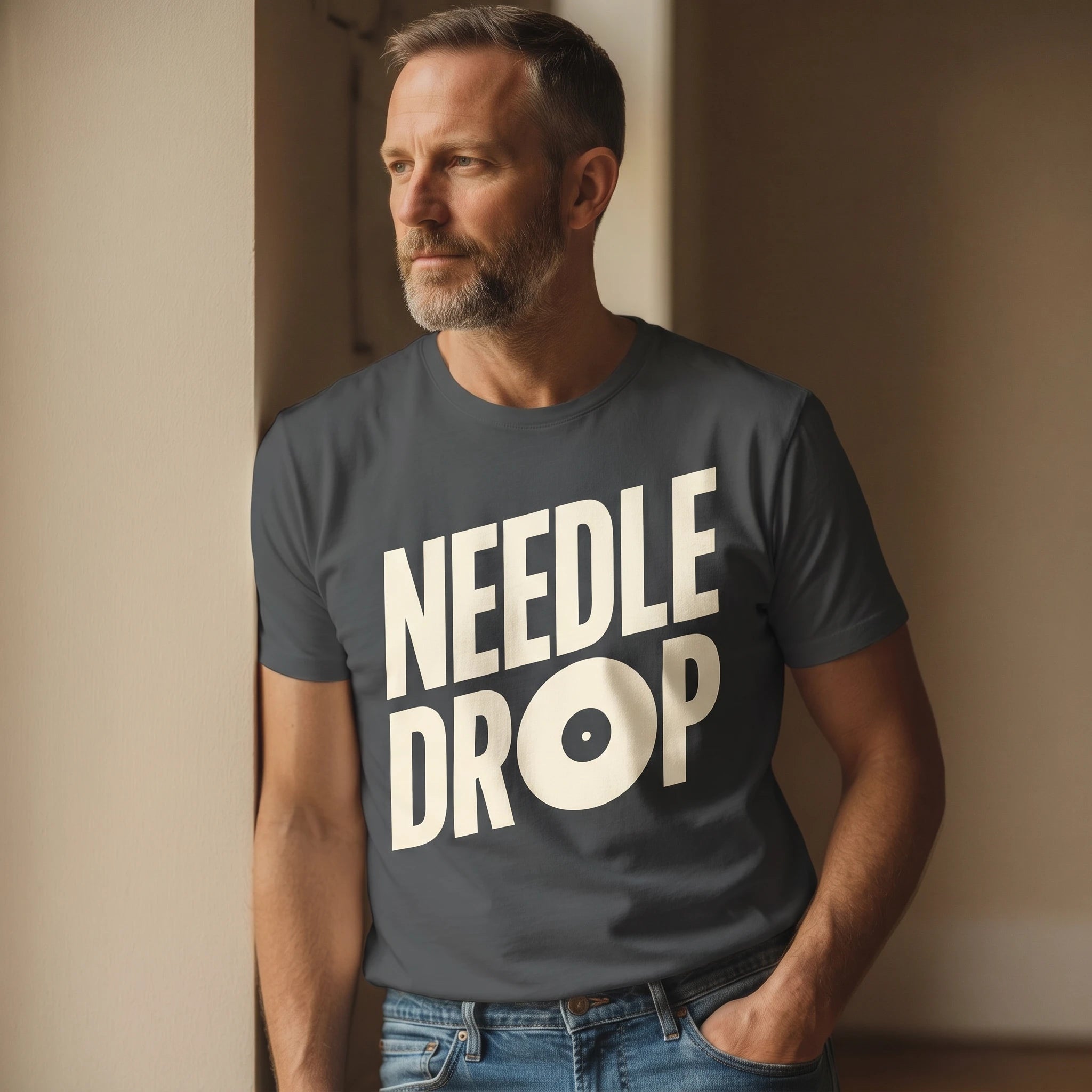 Man wearing a t-shirt with 'NEEDLE DROP' text against a plain wall.