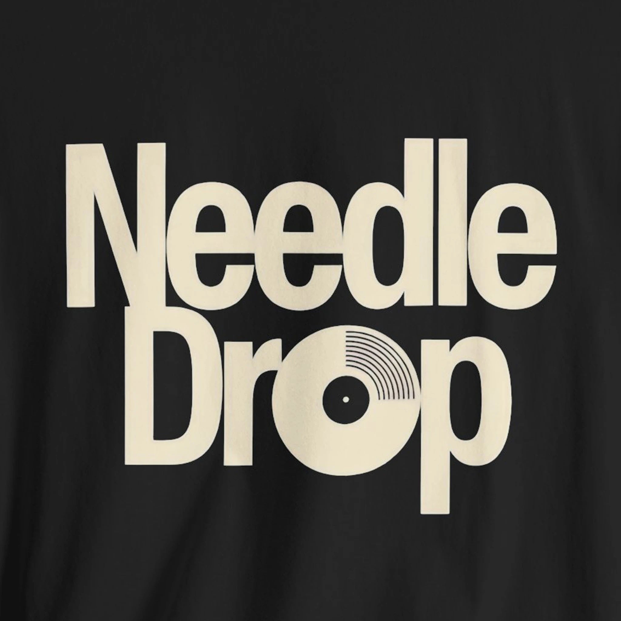 Black t-shirt with 'Needle Drop' text in beige on a black background