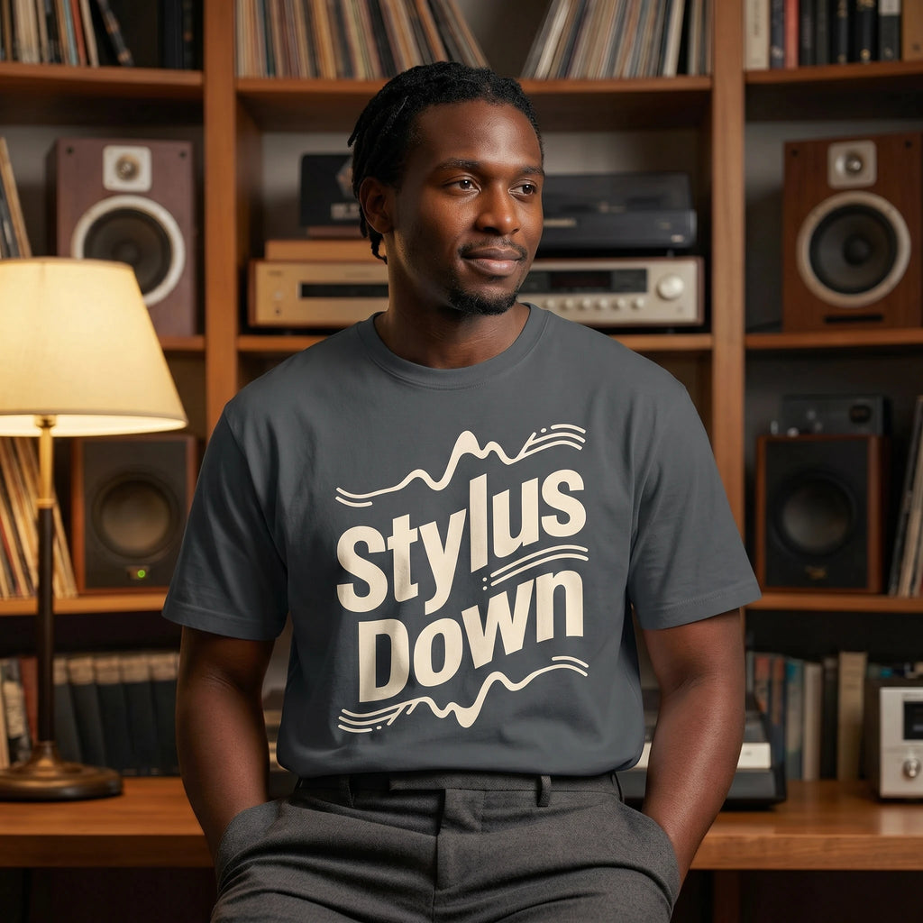 Man wearing a 'Stylus Down' t-shirt in a room with record players and books.