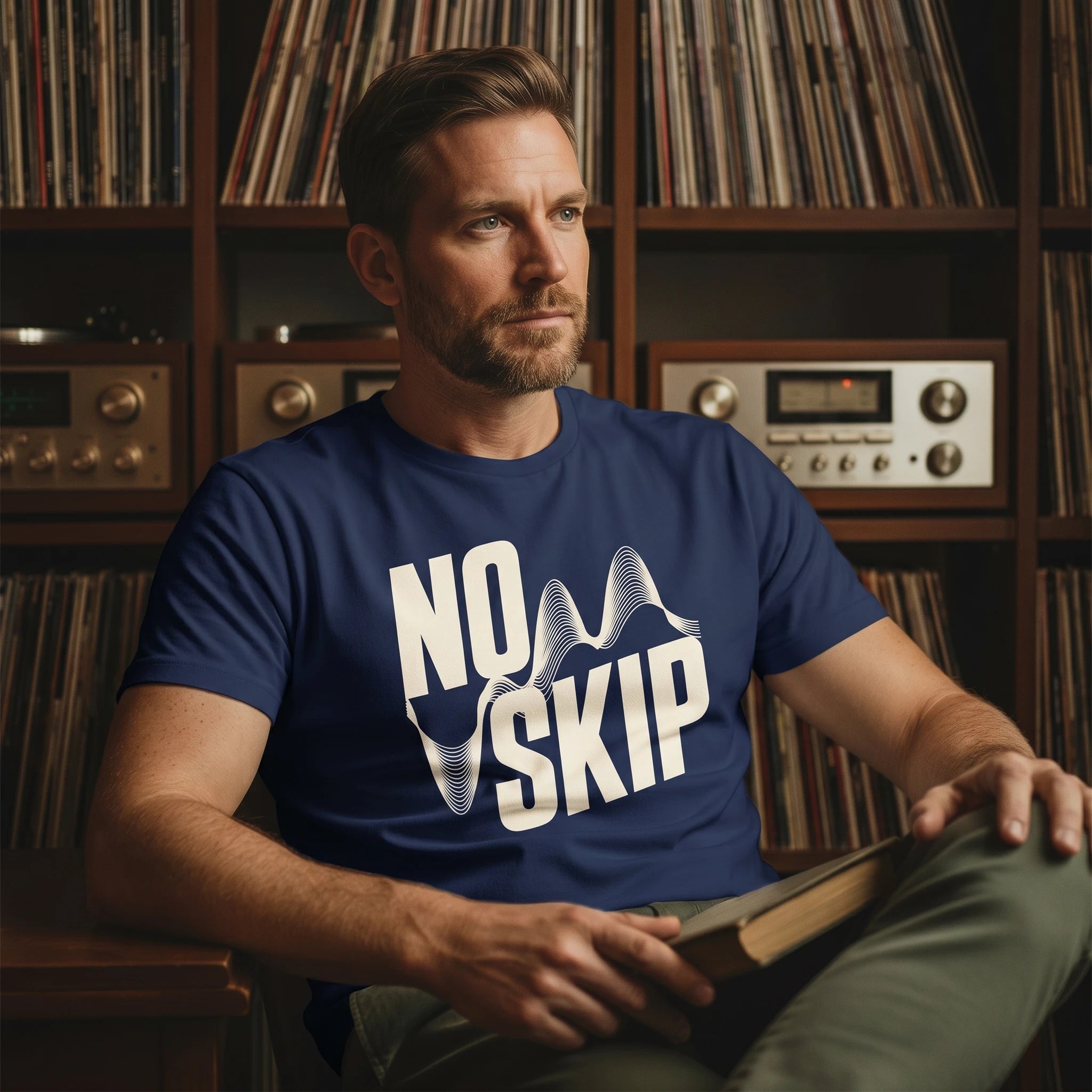Man wearing a blue 'NO SKIP' t-shirt sitting in front of a record player and records.