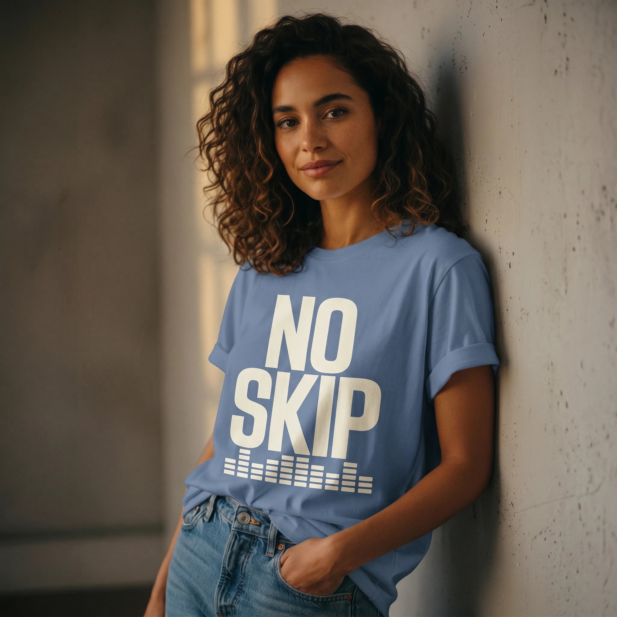 Woman wearing a blue t-shirt with 'NO SKIP' text against a textured wall.