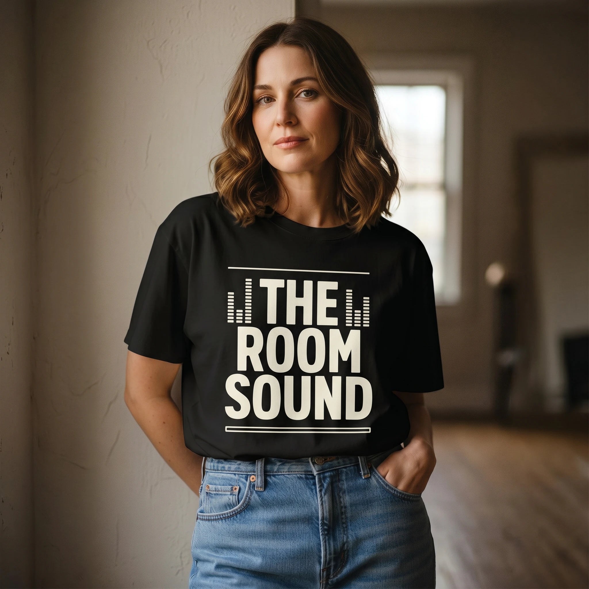 Woman wearing a black t-shirt with 'THE ROOM SOUND' text in a room.