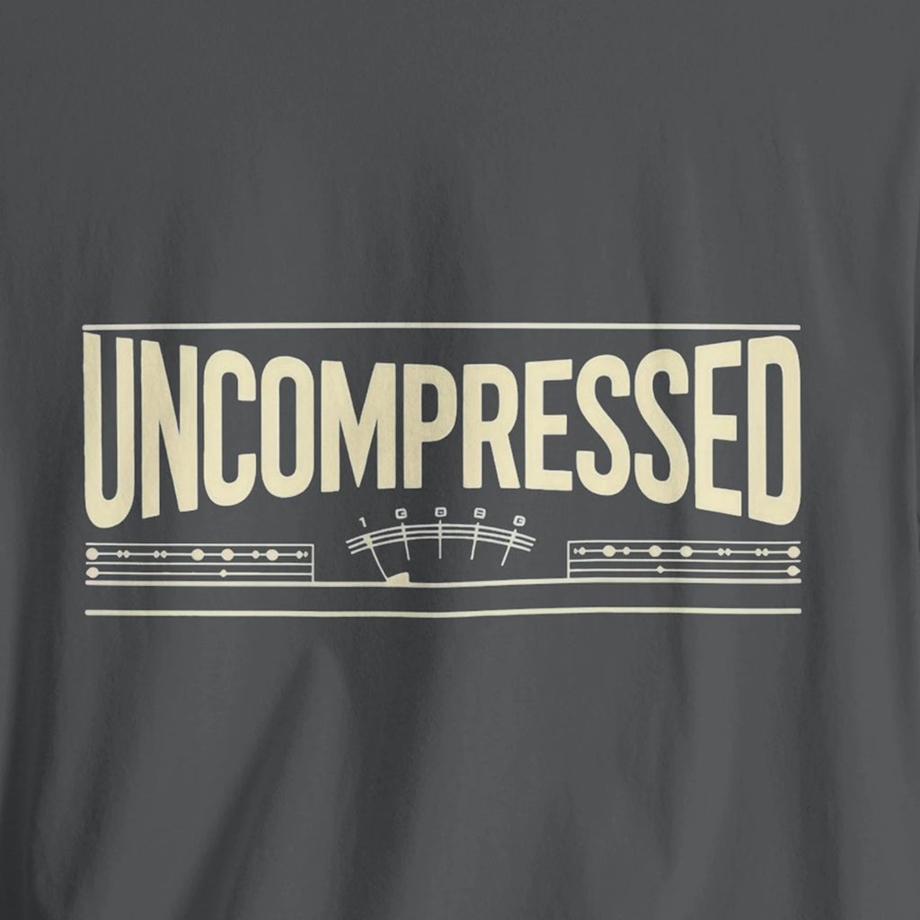 Gray t-shirt with 'UNCOMPRESSED' text and musical notes design on a dark background