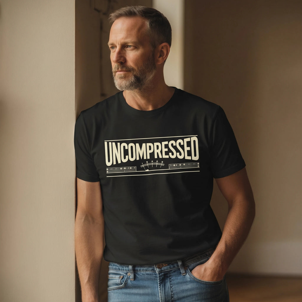 Man wearing a black t-shirt with 'UNCOMPRESSED' text, standing against a neutral wall.