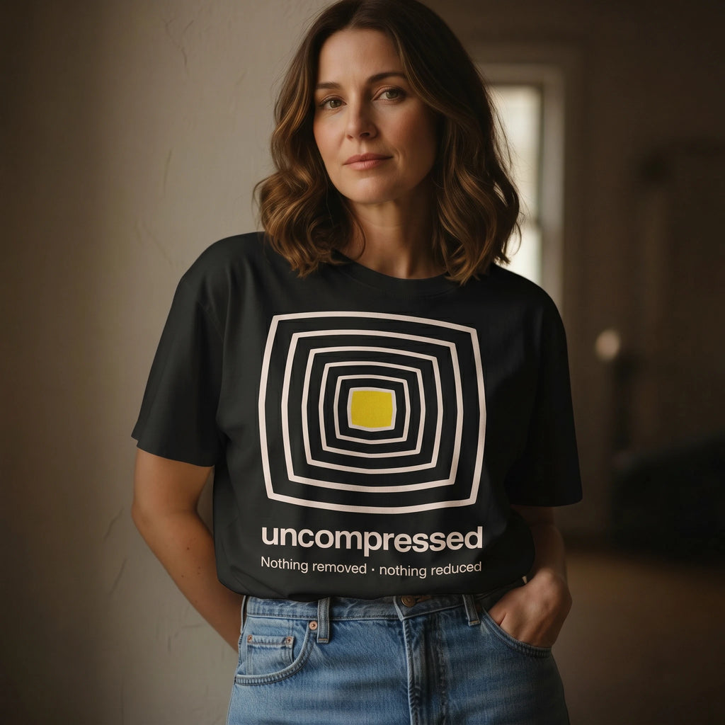 Woman wearing a black t-shirt with a geometric design and text, standing indoors.