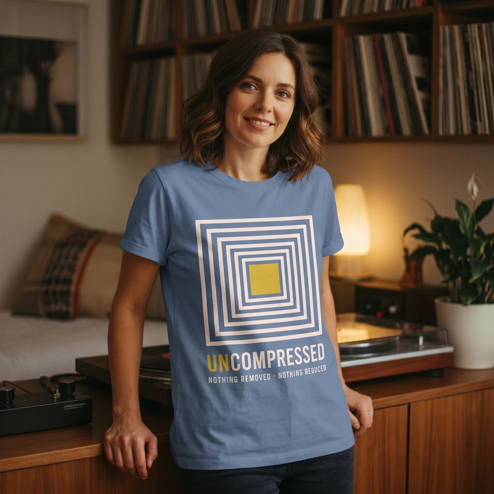 Woman wearing a blue t-shirt with a graphic design in a cozy living room.