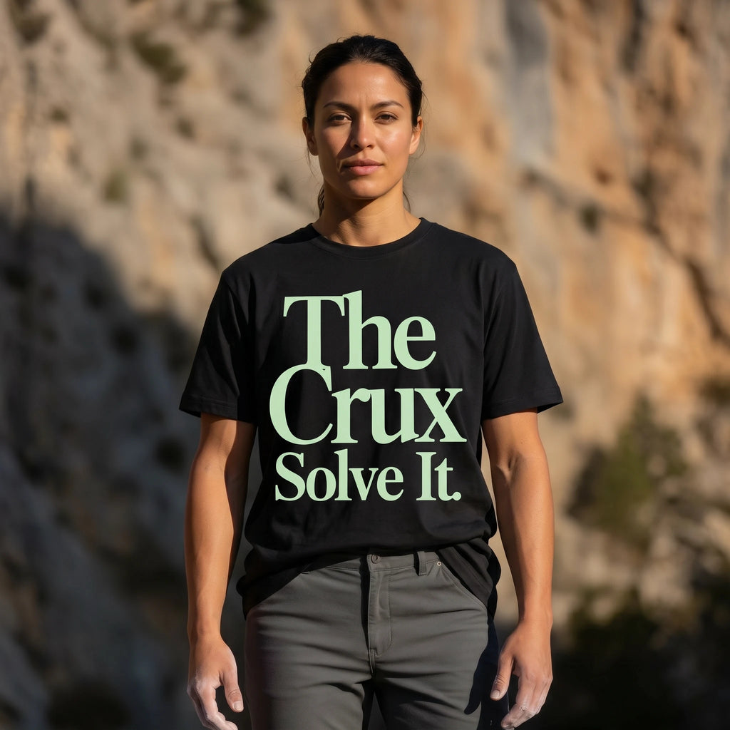 Person wearing a black t-shirt with 'The Crux Solve It' text against a natural background