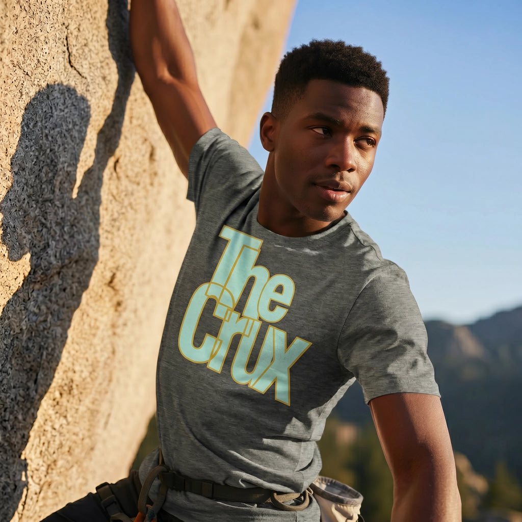 Person wearing a gray t-shirt with 'The Clux' logo against a mountainous background