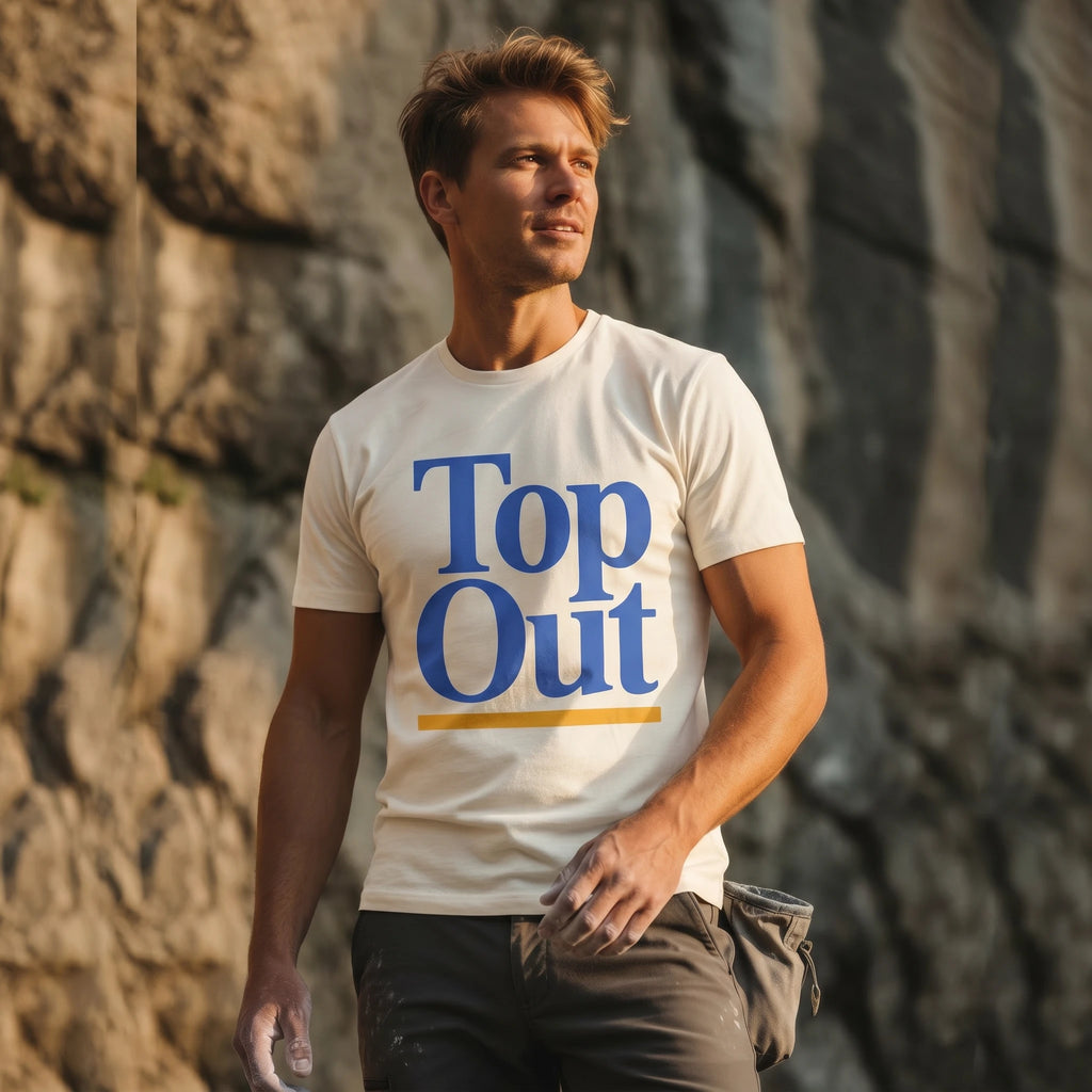 Man wearing a 'Top Out' t-shirt standing against a rocky background