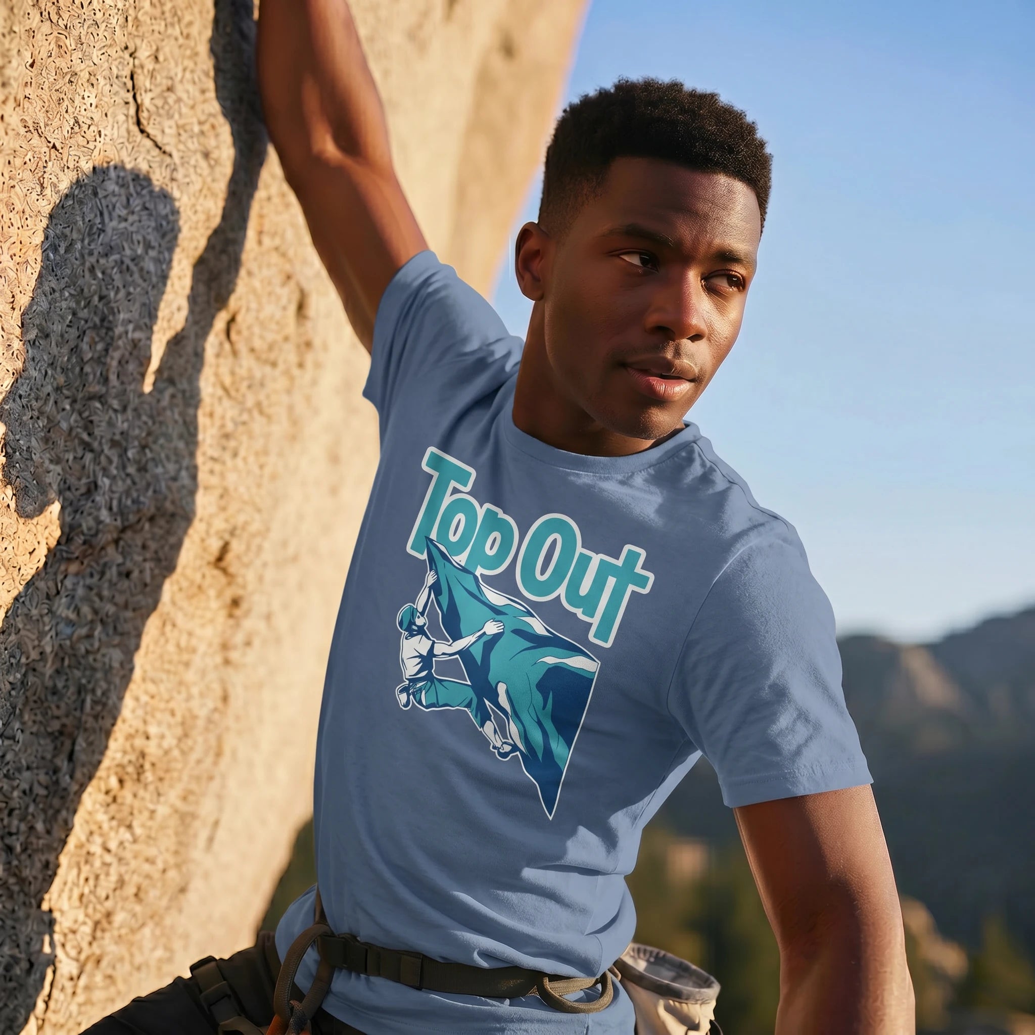 Person wearing a 'Top Out' t-shirt in a mountainous outdoor setting