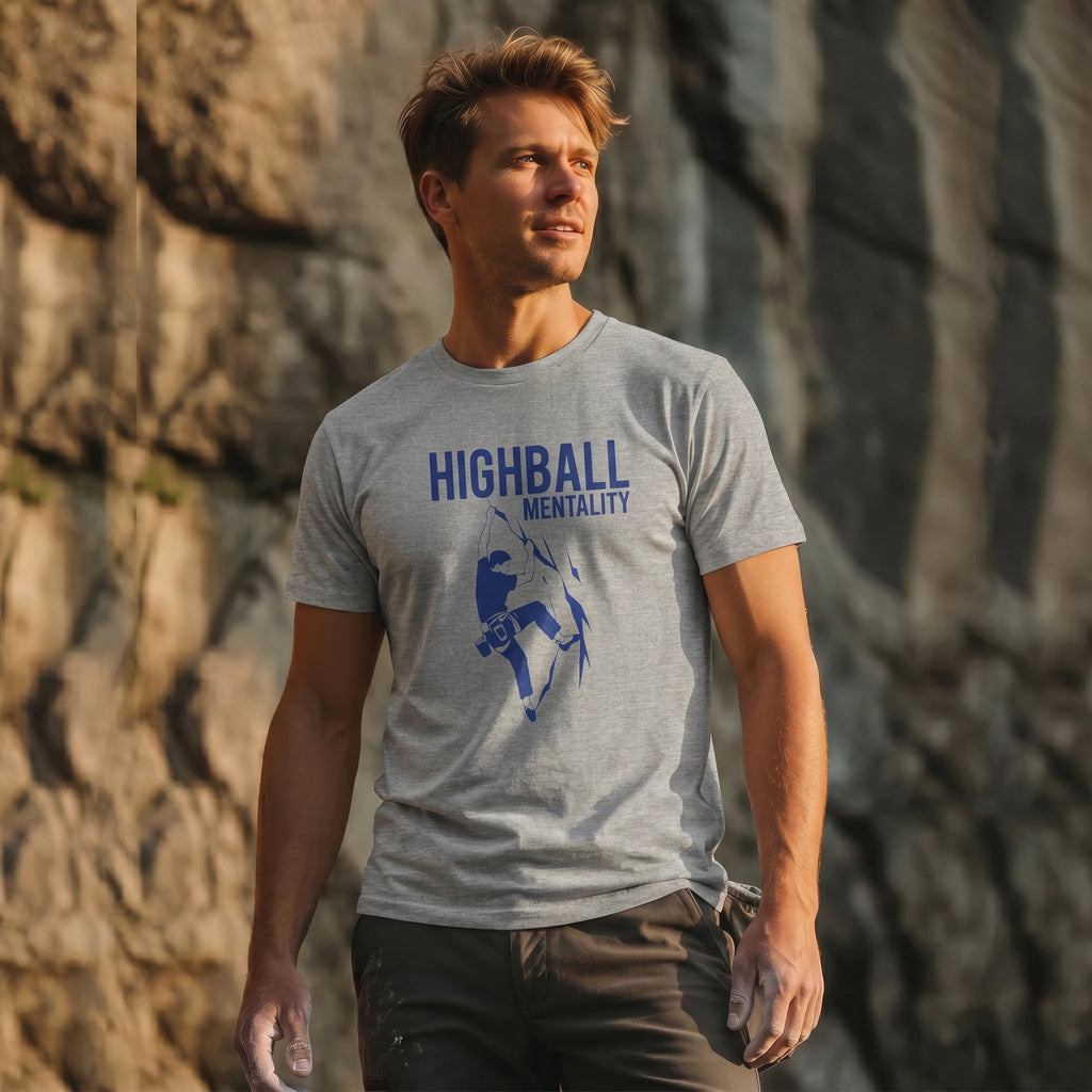 Man wearing a gray t-shirt with 'Highball Mentality' graphic design against a stone wall.
