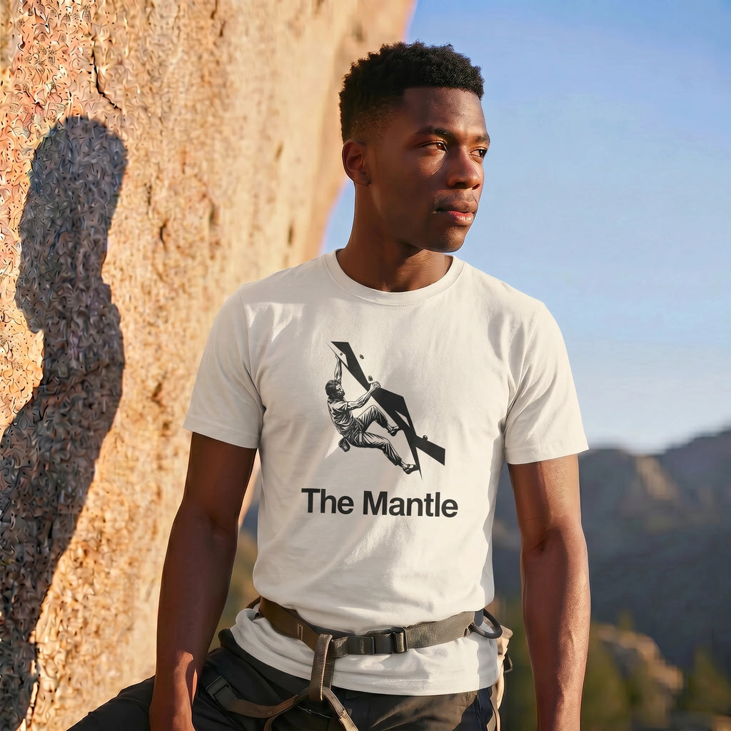Man wearing a t-shirt with 'The Mantle' graphic and climbing silhouette against a mountainous background