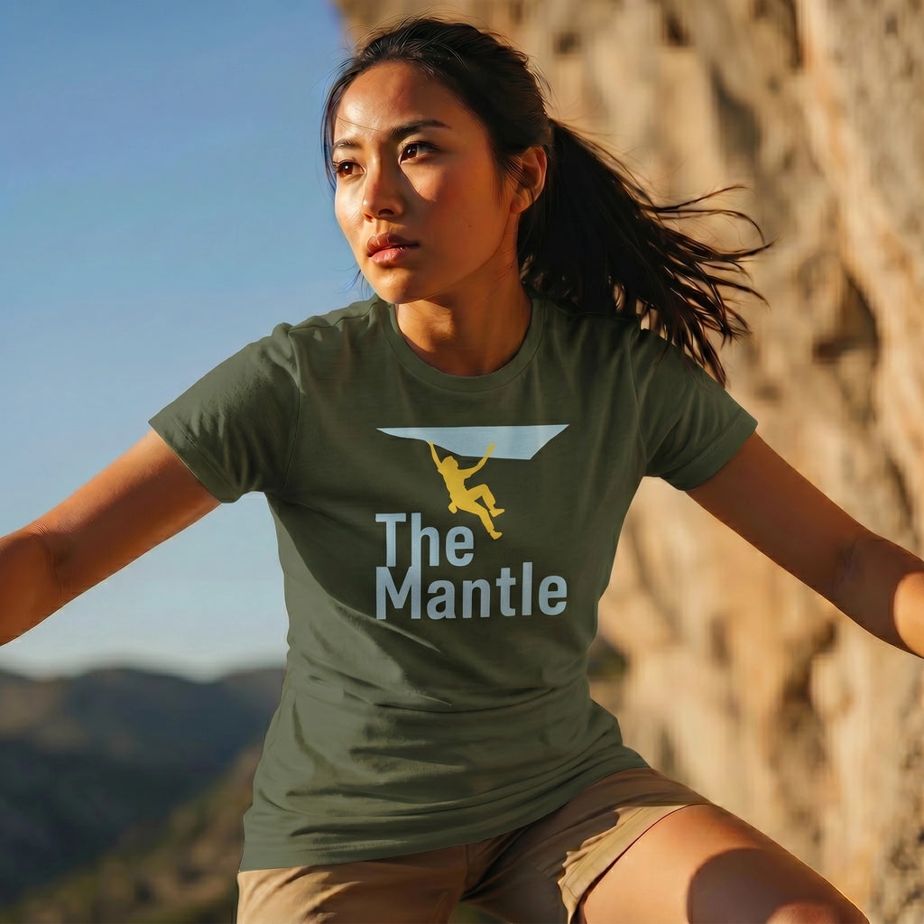 Woman wearing a green 'The Mantle' t-shirt with a climbing graphic, standing against a natural rock background.