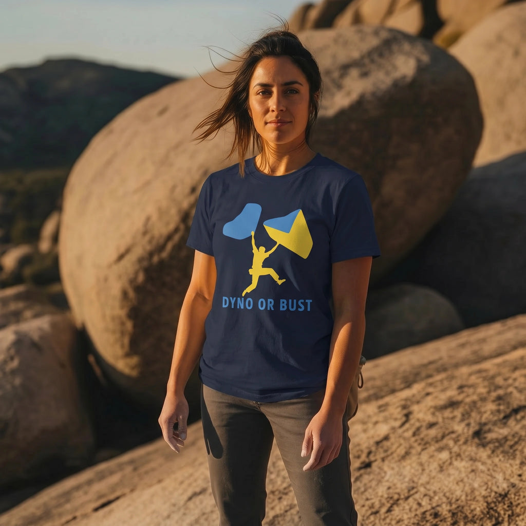 Woman wearing a blue t-shirt with a graphic design and 'Dyno or Bust' text, standing in a rocky outdoor setting.