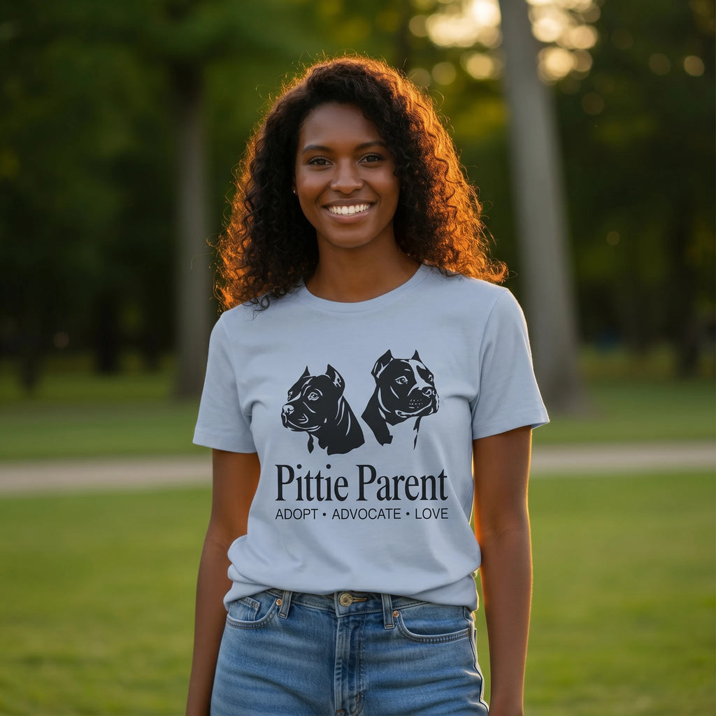 Woman wearing a 'Pittie Parent' t-shirt with dog illustrations in a park setting