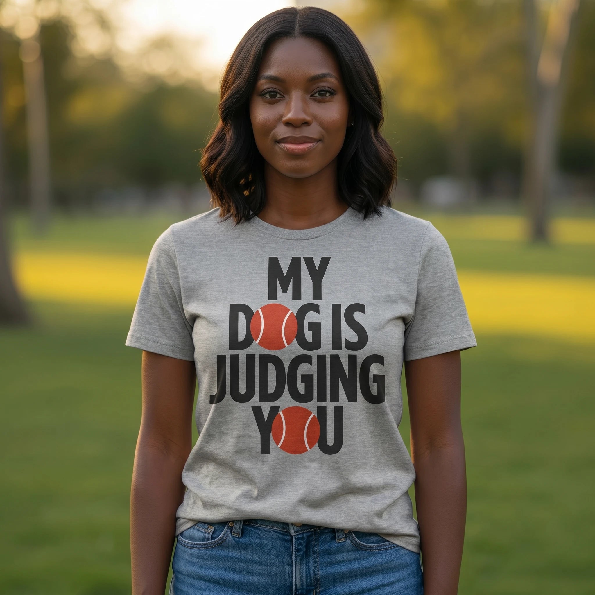Person wearing a gray t-shirt with 'My dog is judging you' text in a park.