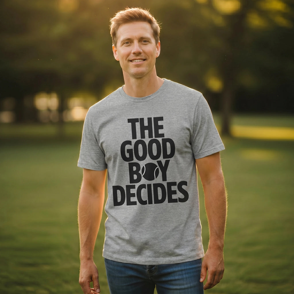 Man wearing a gray t-shirt with 'THE GOOD BOY DECIDES' text in a park setting