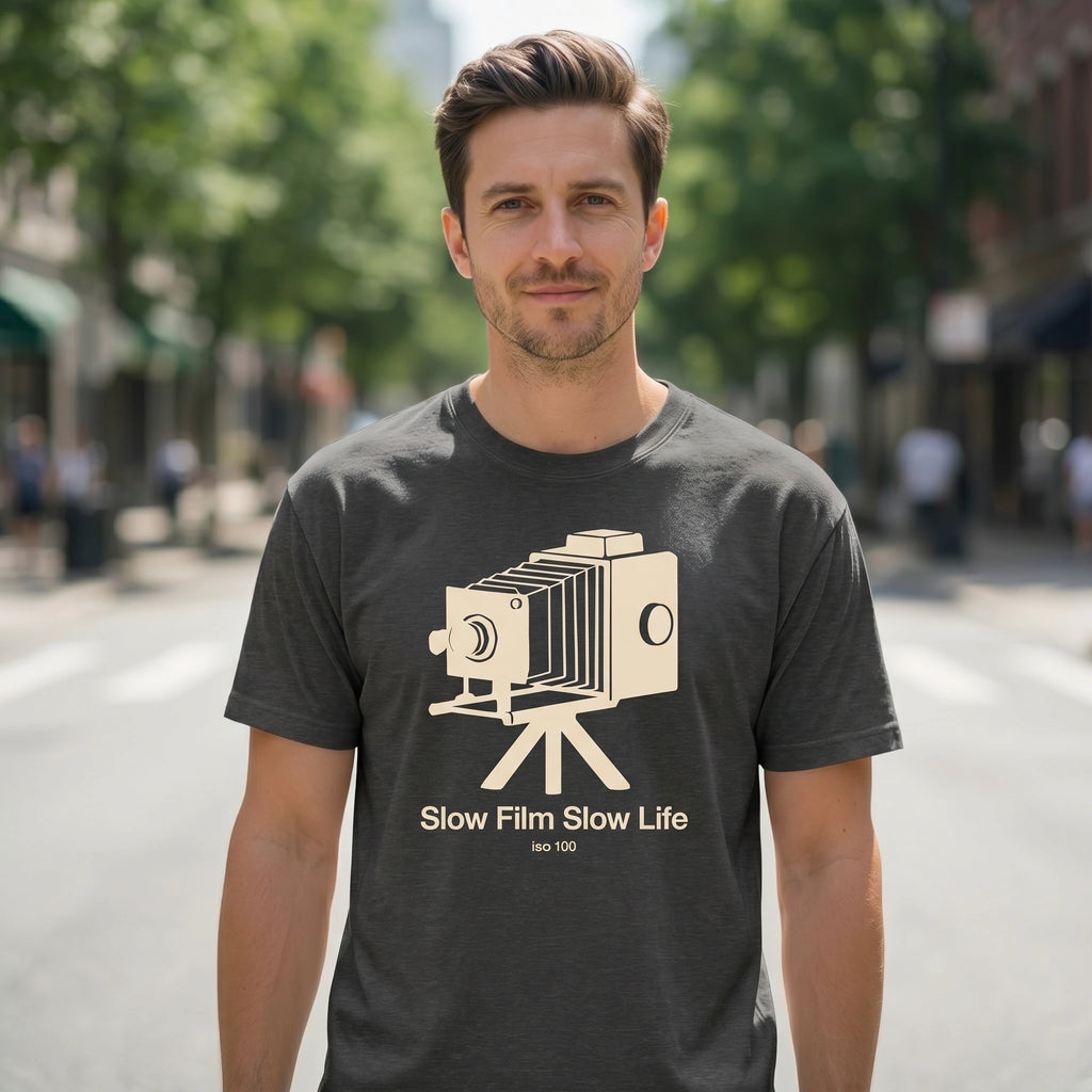 Man wearing a t-shirt with a vintage camera graphic and 'SLOW FILM SLOW LIFE' text on a street background