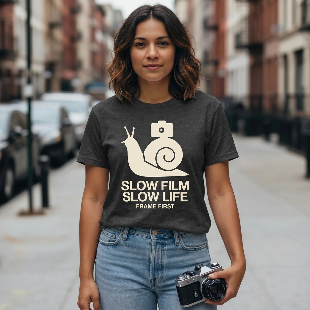 Woman wearing a t-shirt with a snail and camera graphic and text on a city street.