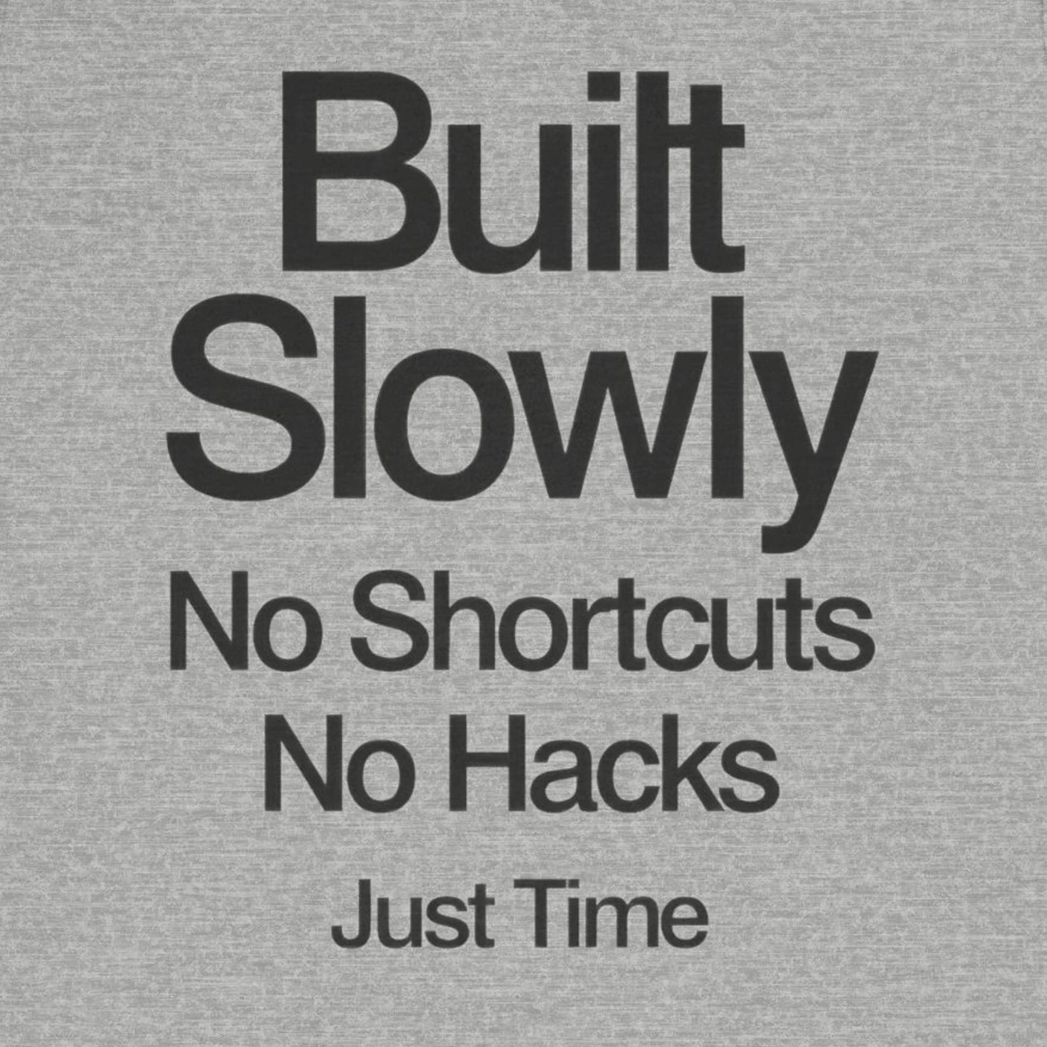 Gray t-shirt with black text 'Built Slowly No Shortcuts No Hacks Just Time' on a plain background