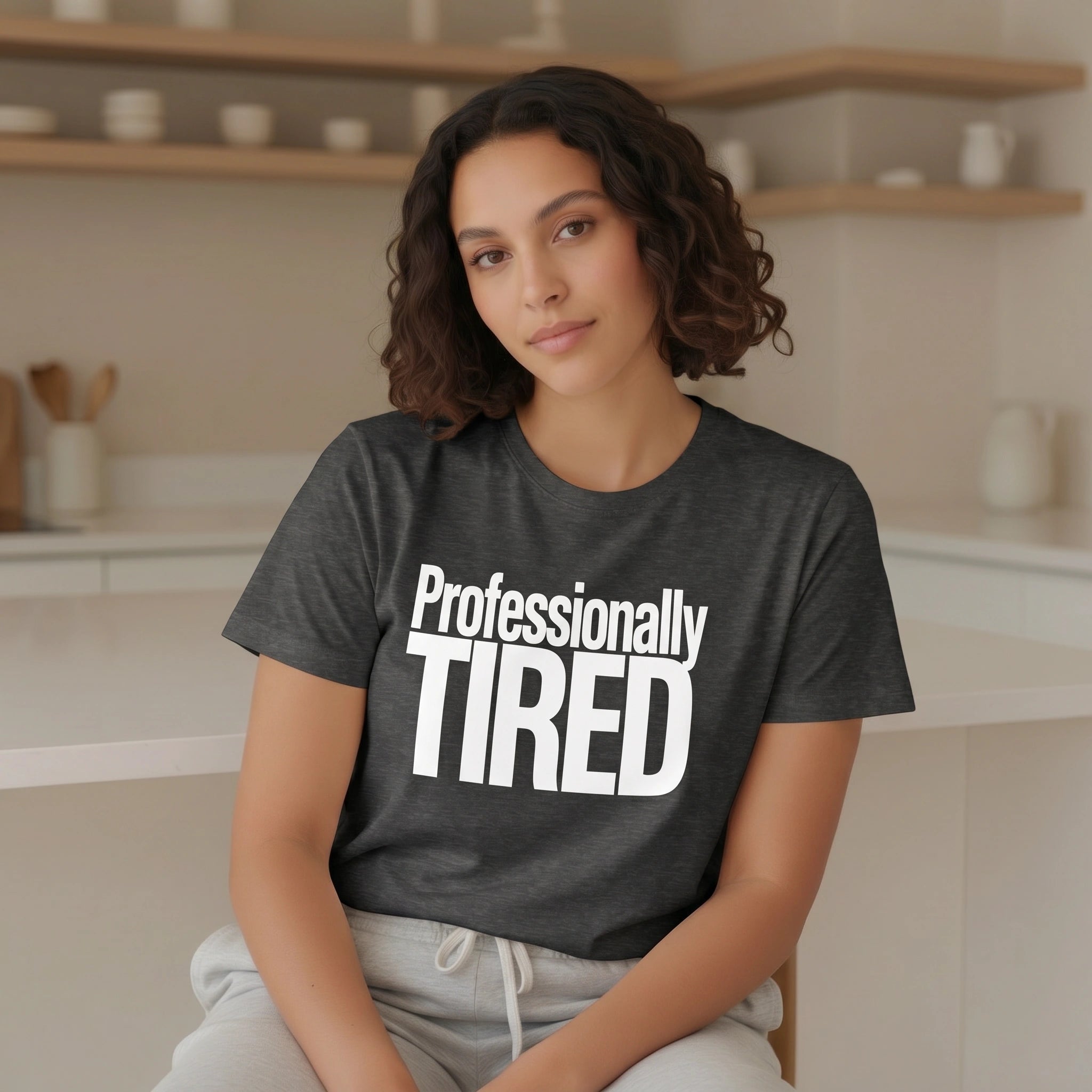Woman wearing a black t-shirt with 'Professionally TIRED' text in a kitchen setting