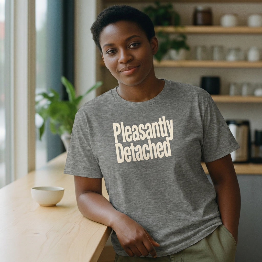 Person wearing a gray t-shirt with 'Pleasantly Detached' text in a casual setting.