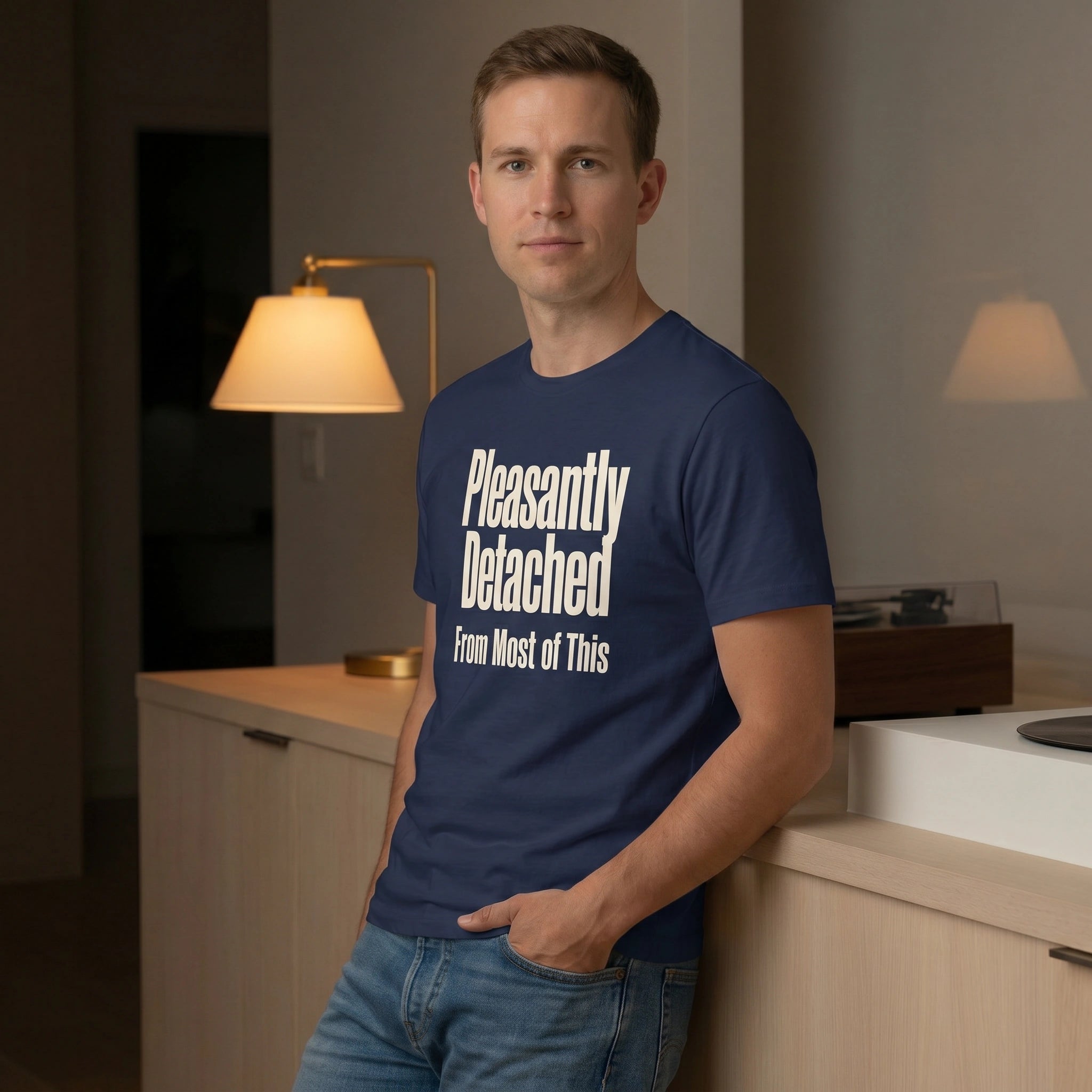 Man wearing a navy blue t-shirt with text in a room with lamps and furniture.