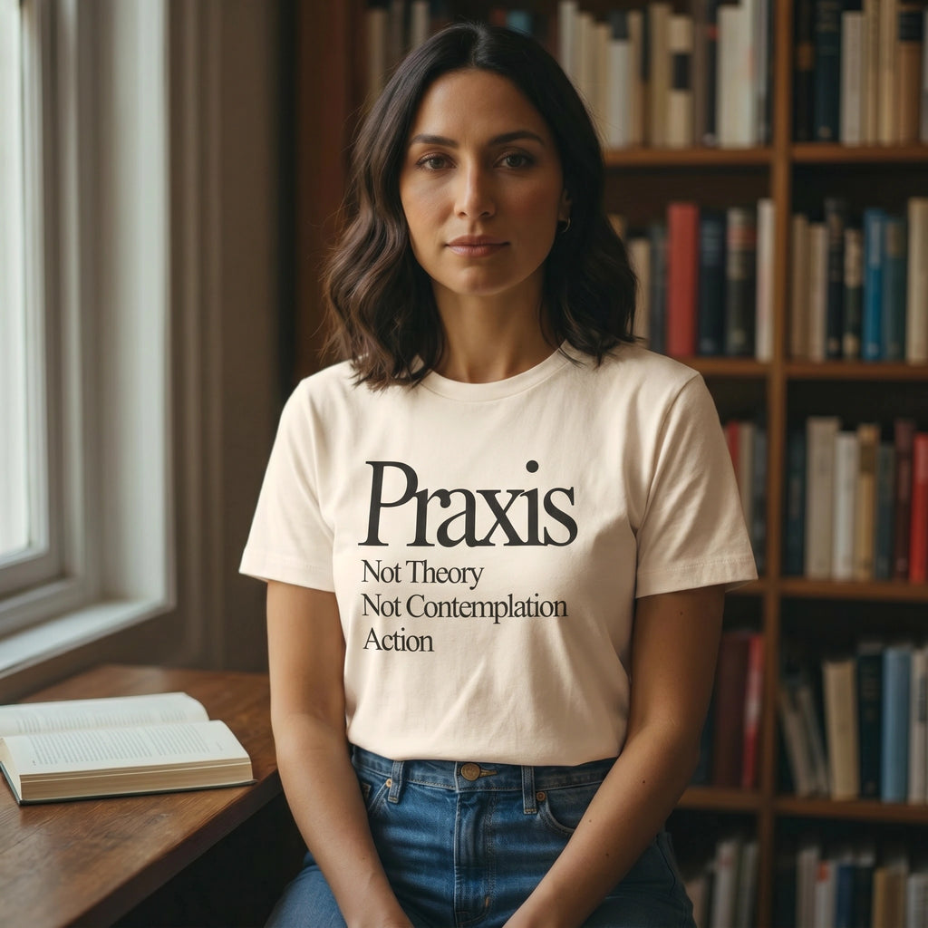 Woman wearing a t-shirt with 'Praxis Not Theory Not Contemplation Action' text in a library setting.