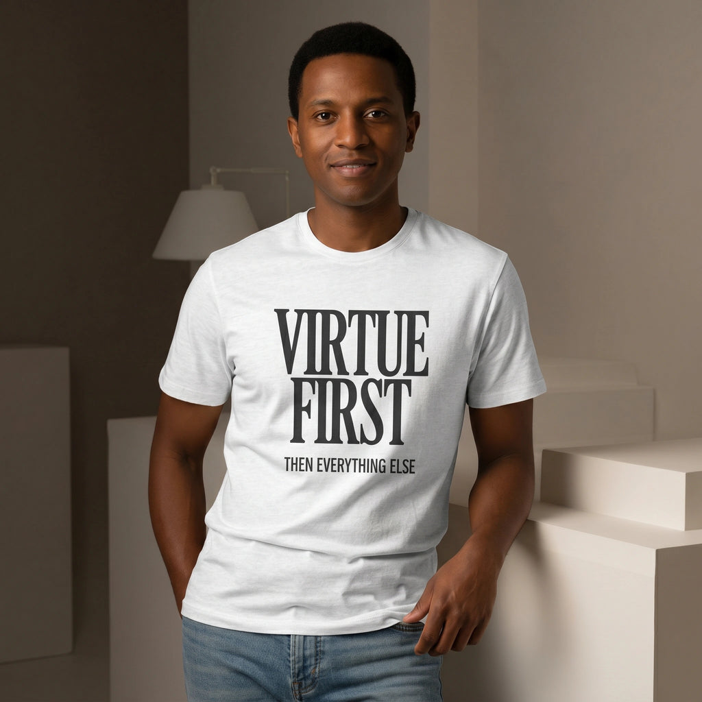 Man wearing a white t-shirt with 'Virtue First, Then Everything Else' text in a minimal indoor setting.