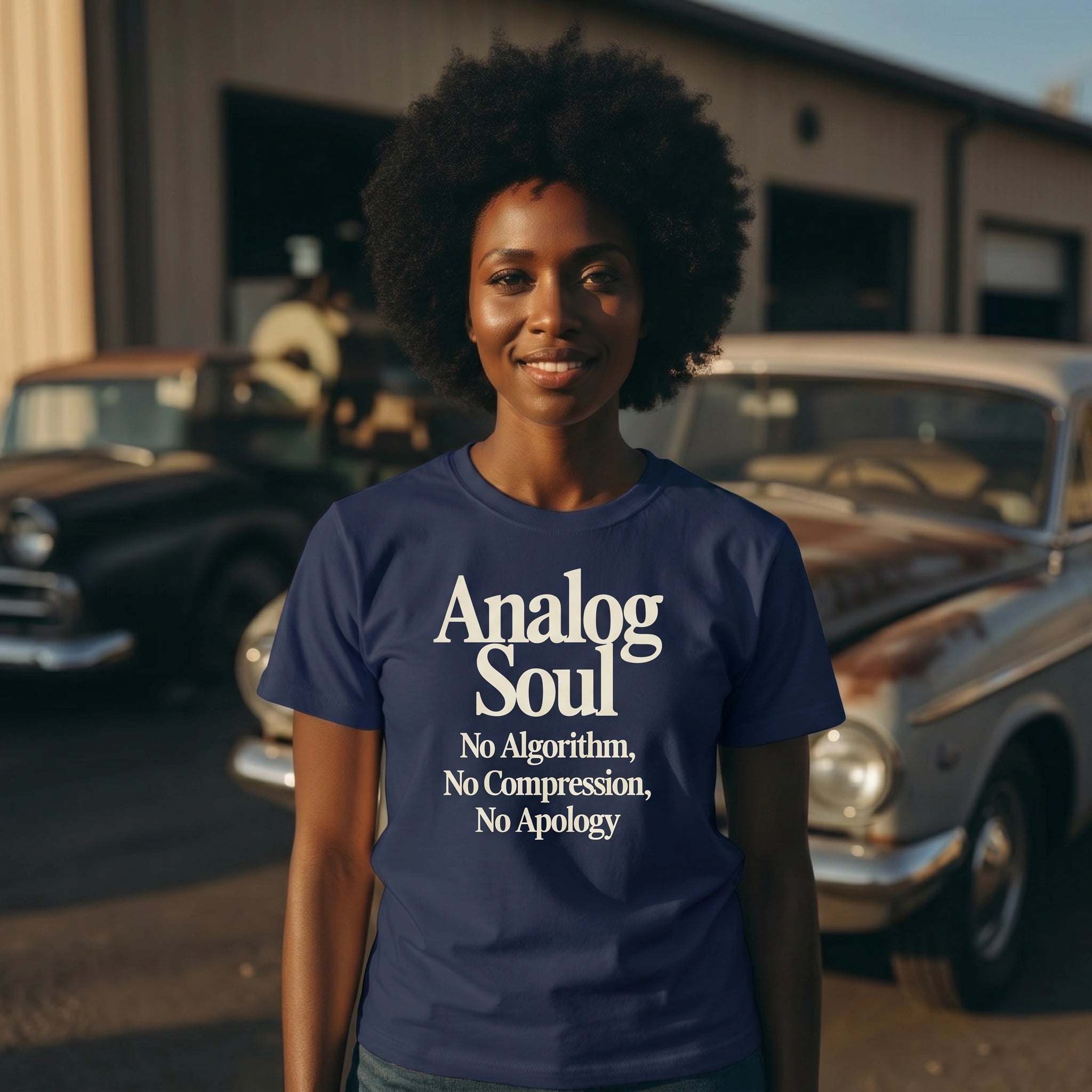 Person wearing a blue t-shirt with 'Analog Soul' text, standing in front of vintage cars.