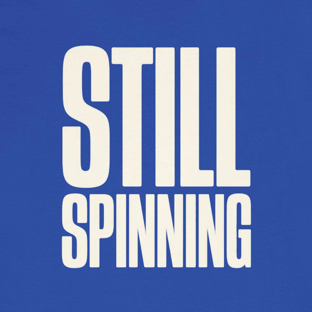 White text 'STILL SPINNING' on a blue background