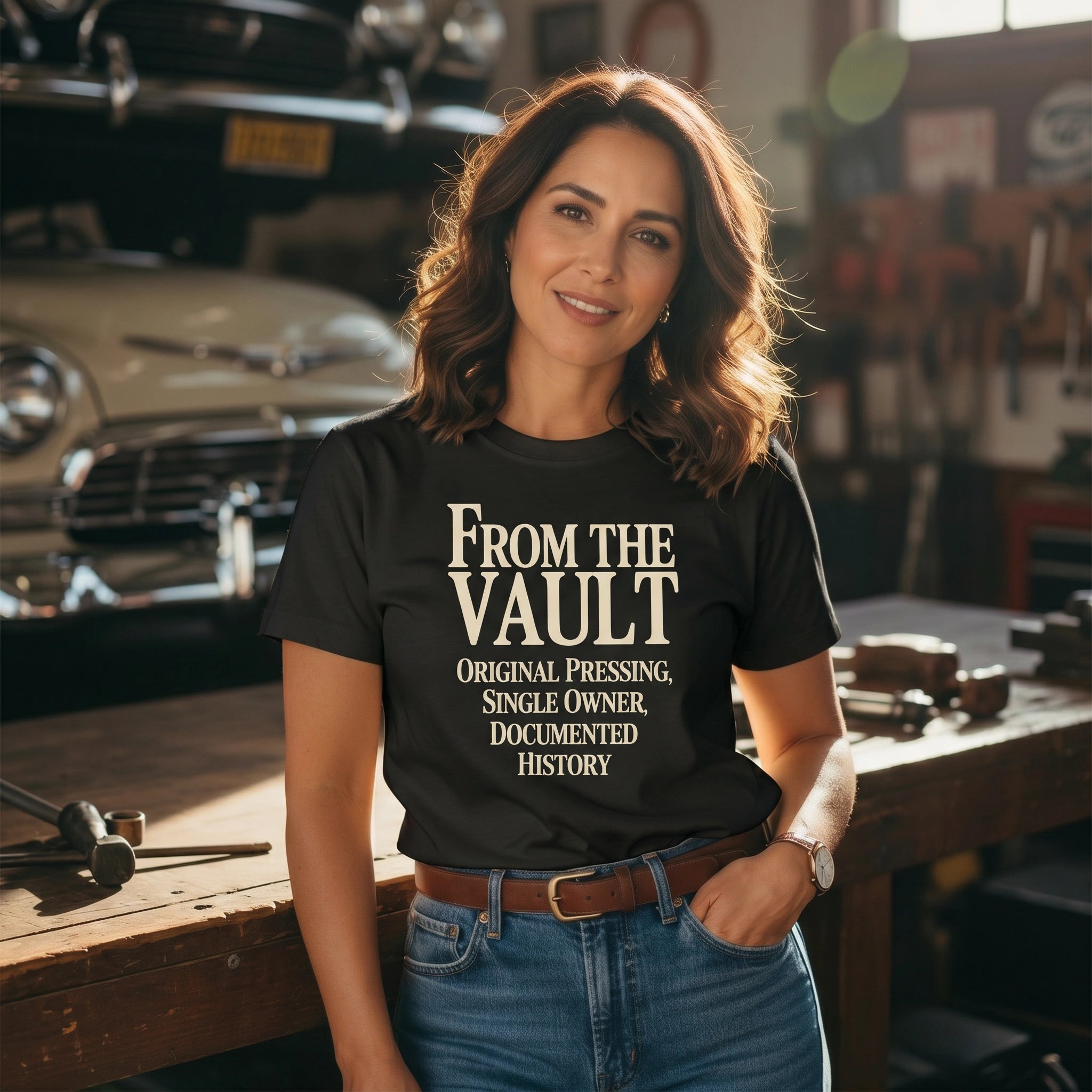 Woman wearing a black t-shirt with 'From The Vault' text in a garage setting