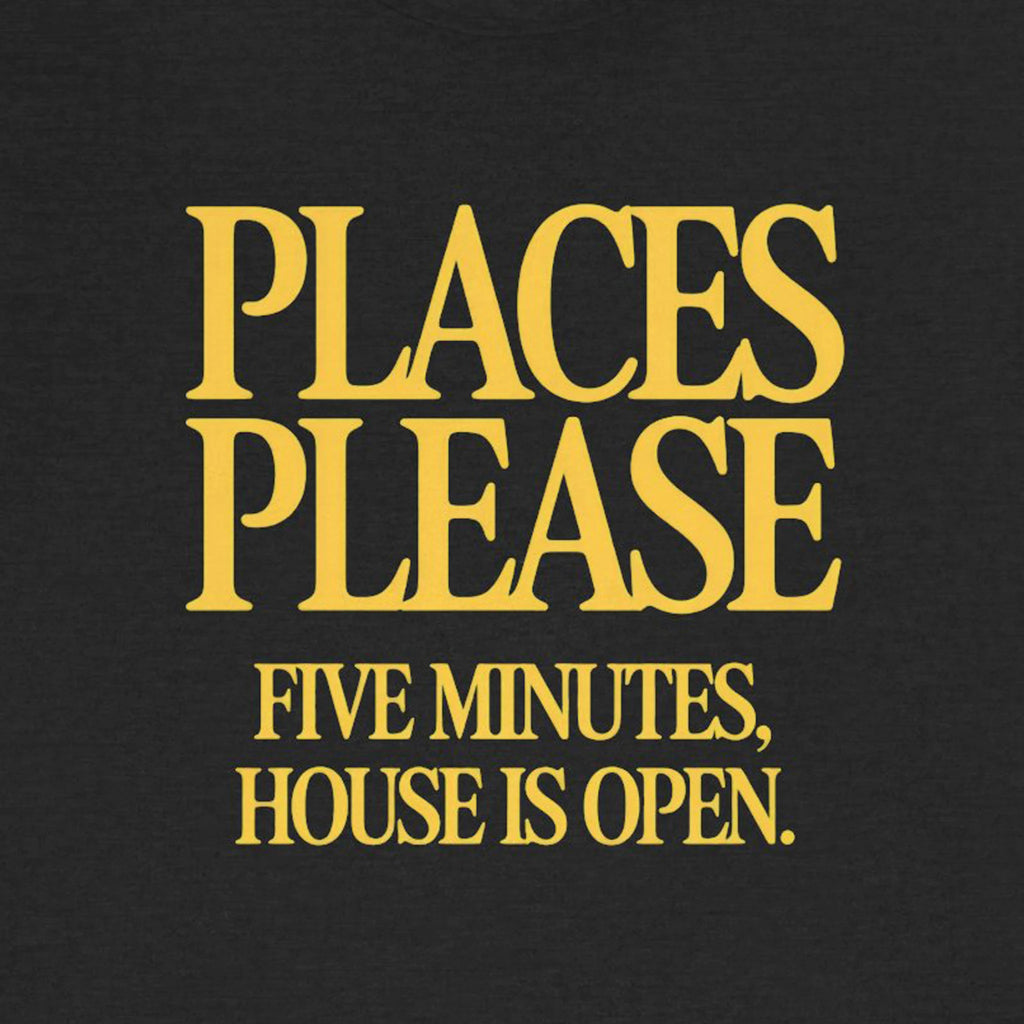 Black t-shirt with yellow text 'PLACES PLEASE FIVE MINUTES, HOUSE IS OPEN.'
