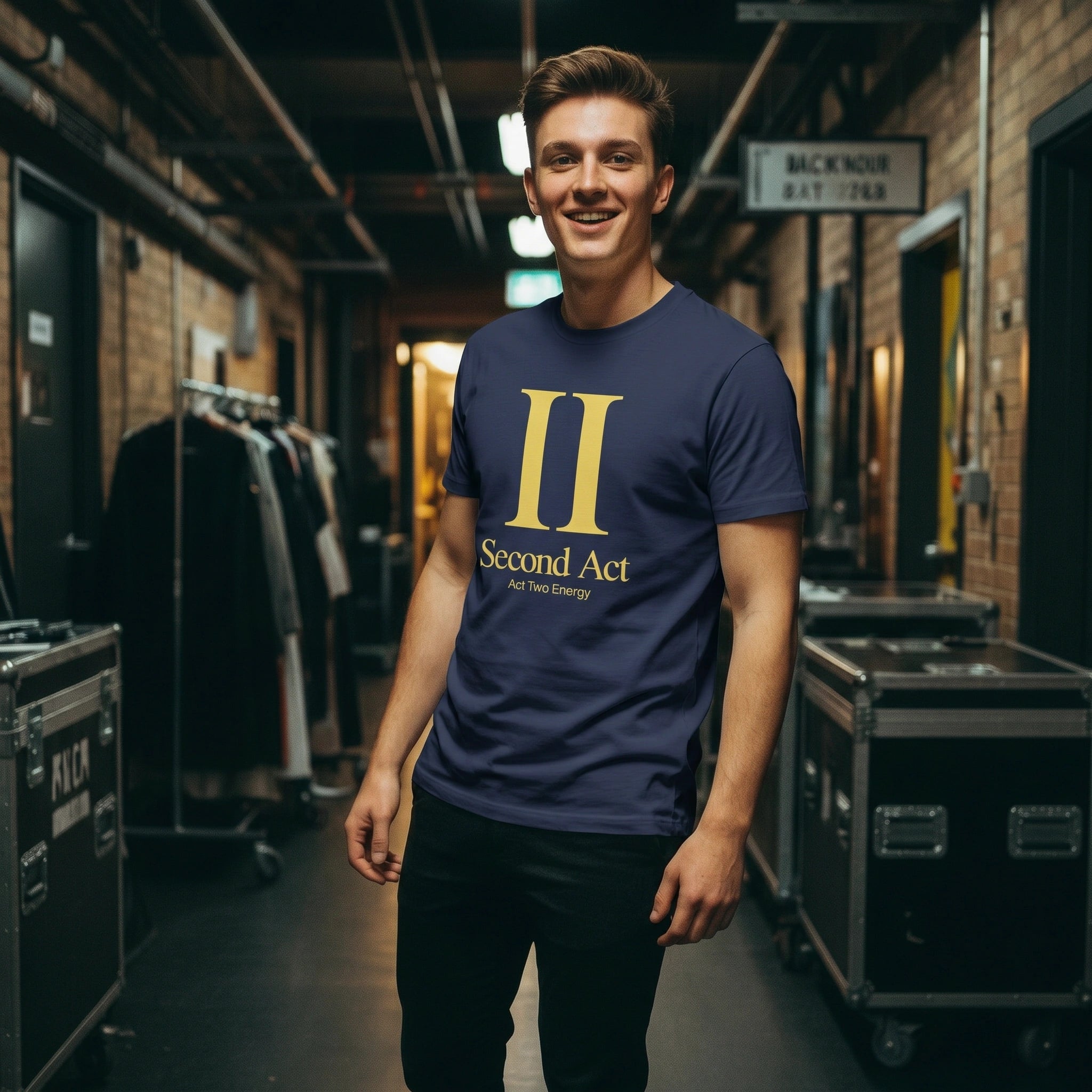 Man wearing a navy blue t-shirt with 'Second Act' logo in a backstage area.