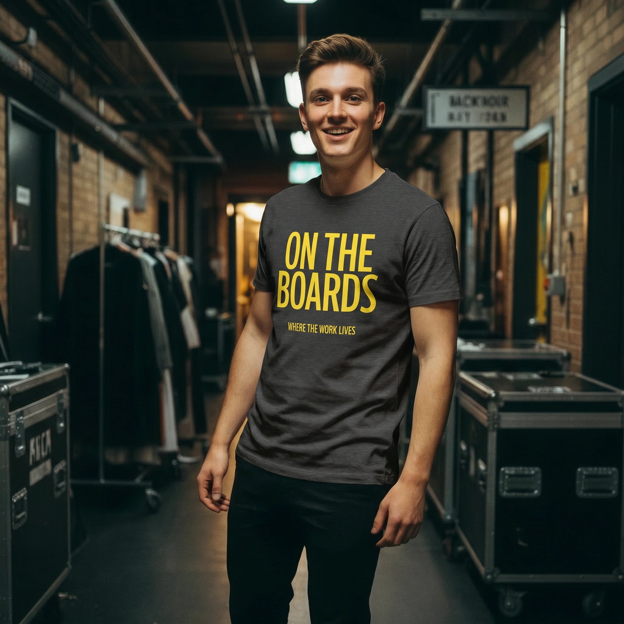 Man wearing a t-shirt with 'On the Boards' text in a backstage area.