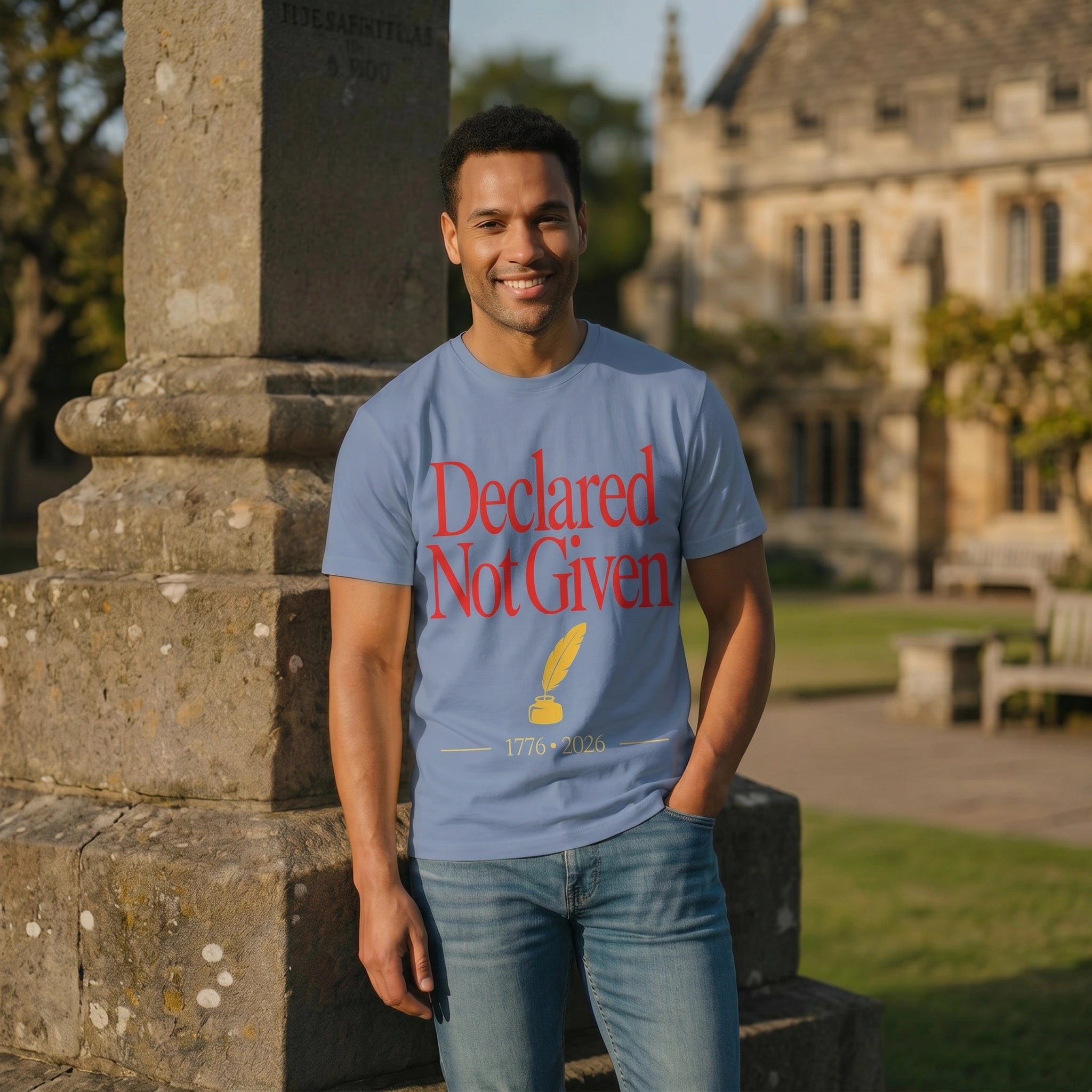 Man wearing a blue t-shirt with red text standing outdoors near a stone building.