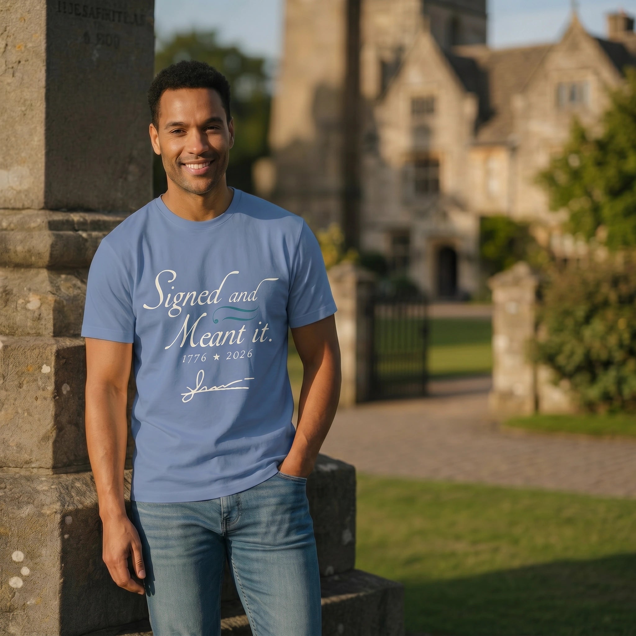 Man wearing a blue t-shirt with text standing outdoors near a stone building.