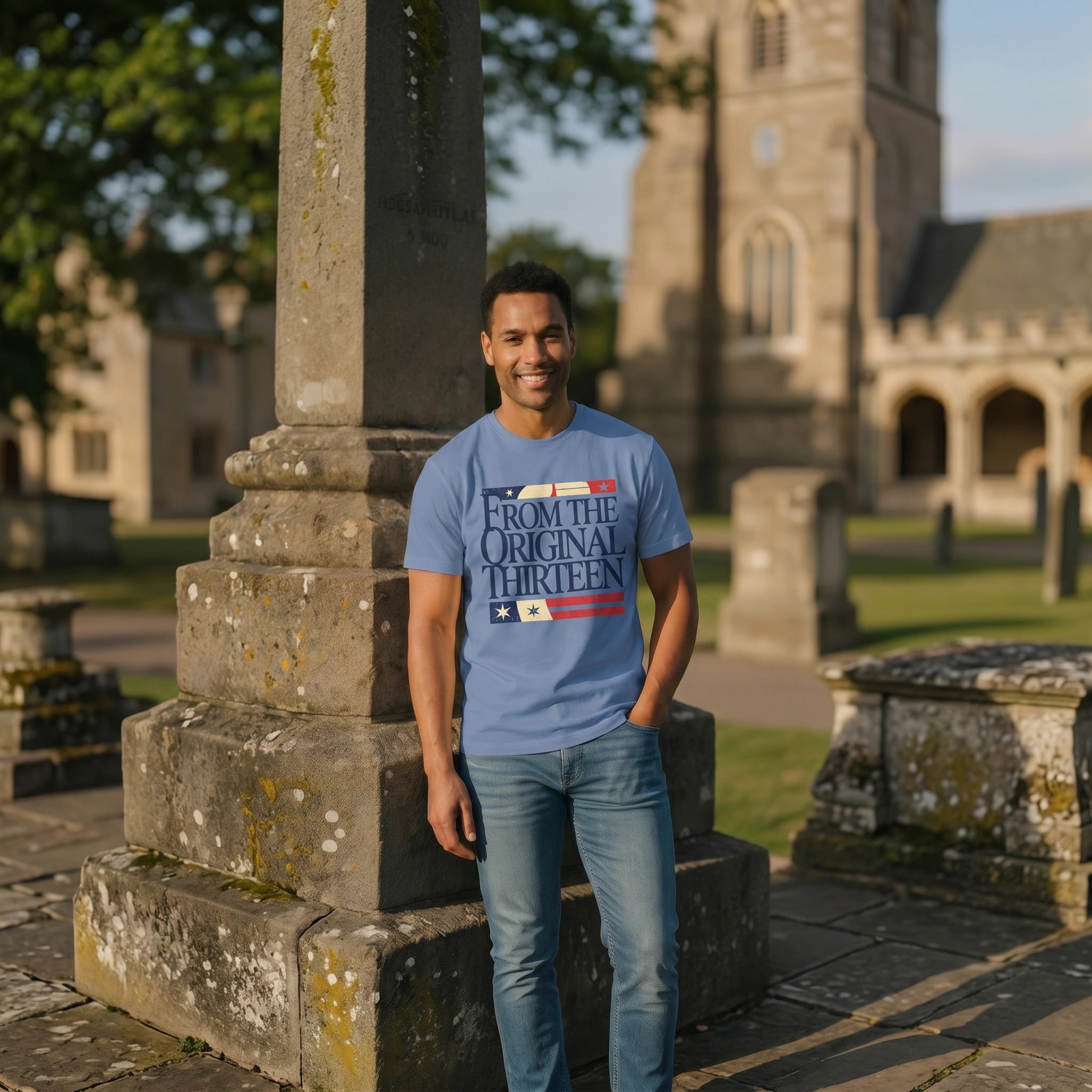 Man wearing a blue t-shirt with text standing in front of a stone monument with a church in the background.